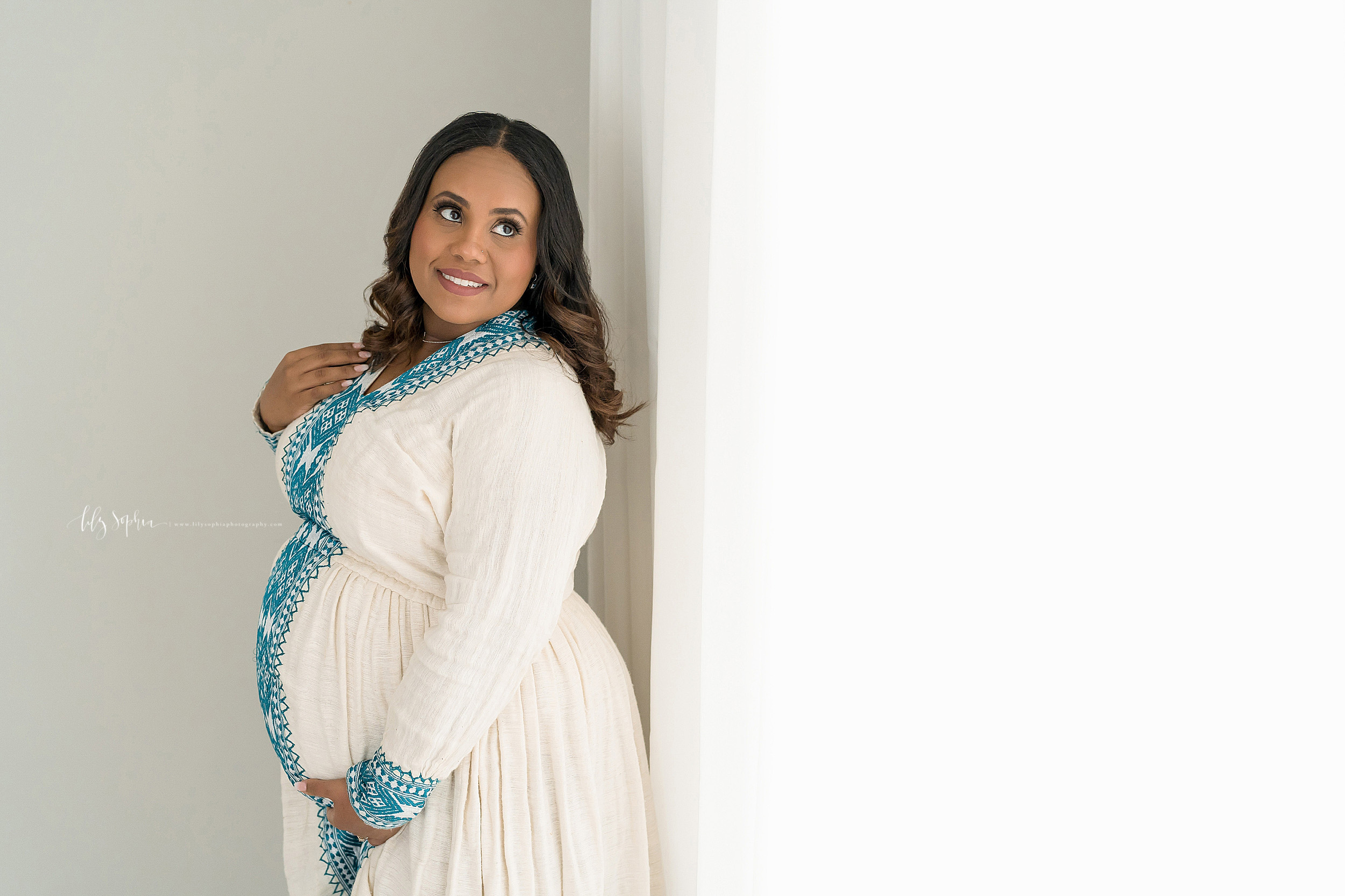  Maternity photo of an Ethiopian woman as she thinks about the impending birth of her child taken in a natural light Atlanta studio. 