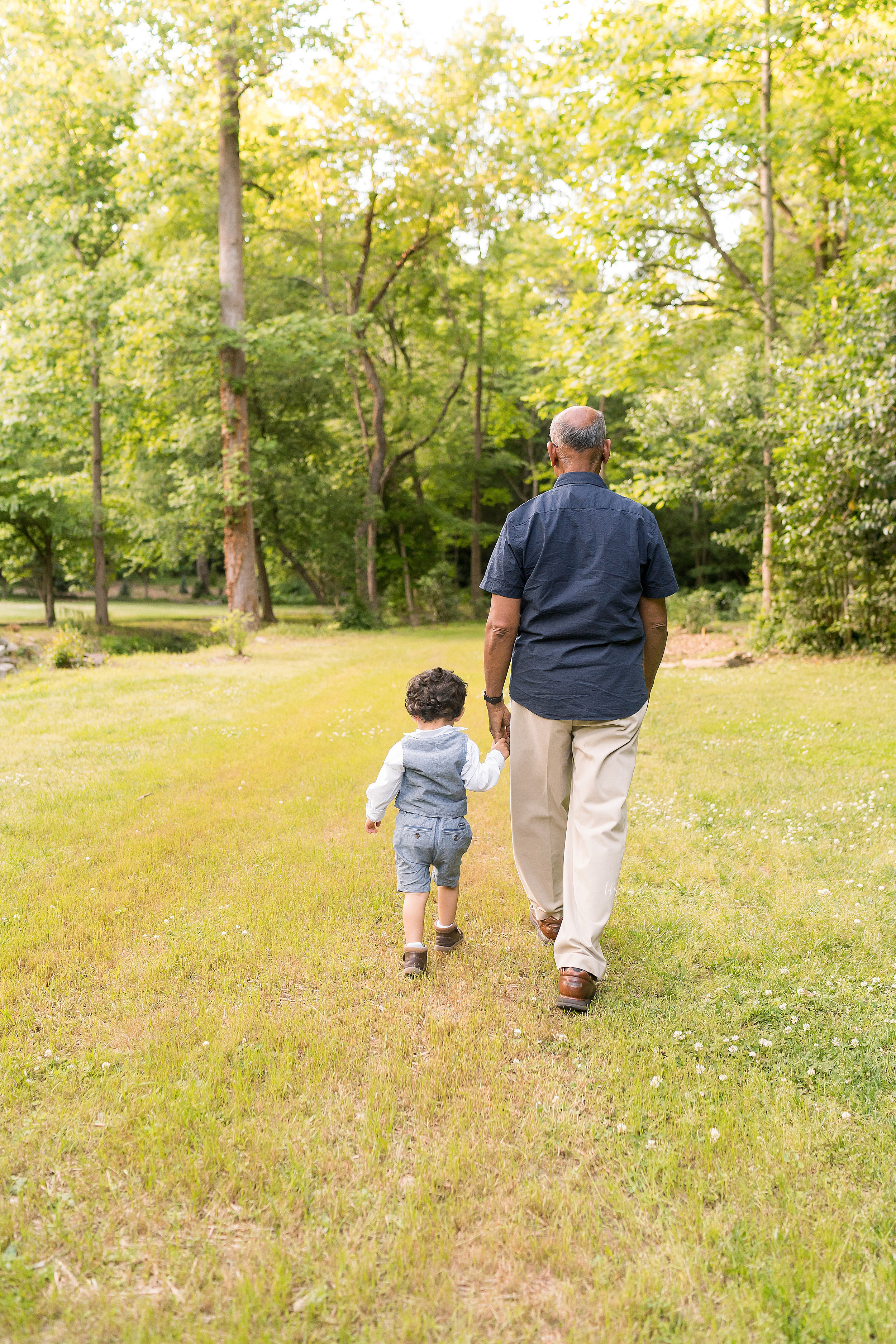  Generational photo of an Indian grandfather and his grandson walking hand in hand in a garden at sunset in Atlanta. 