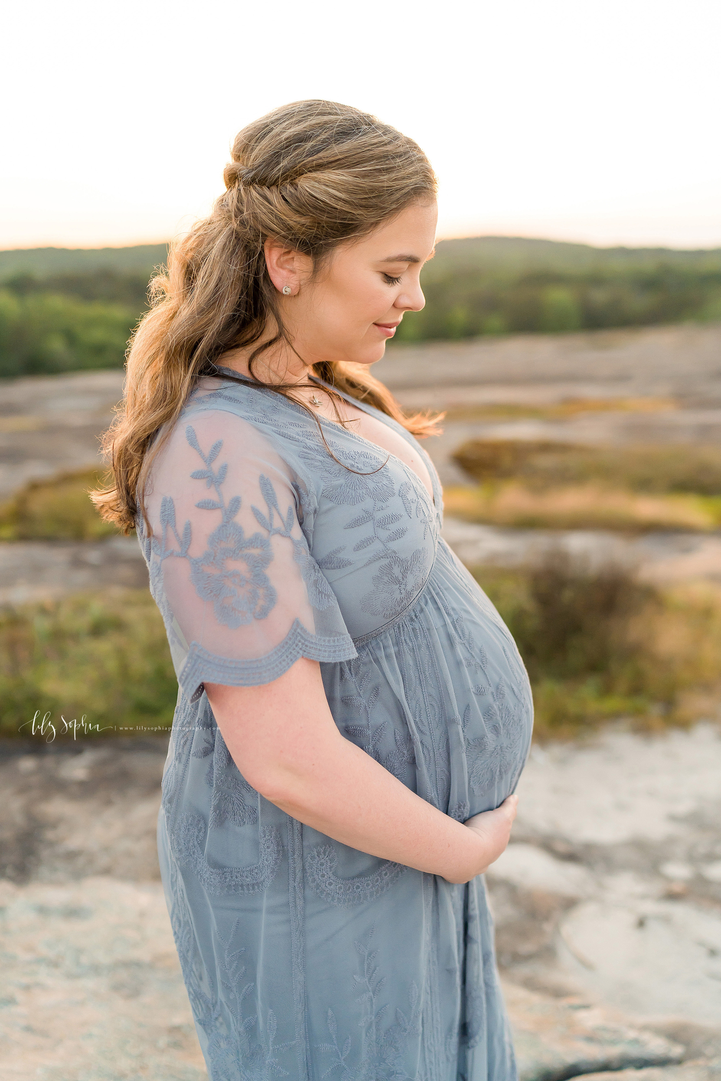  Maternity photo of a contemplative mother as she stands at sunset on an Atlanta mountain. 