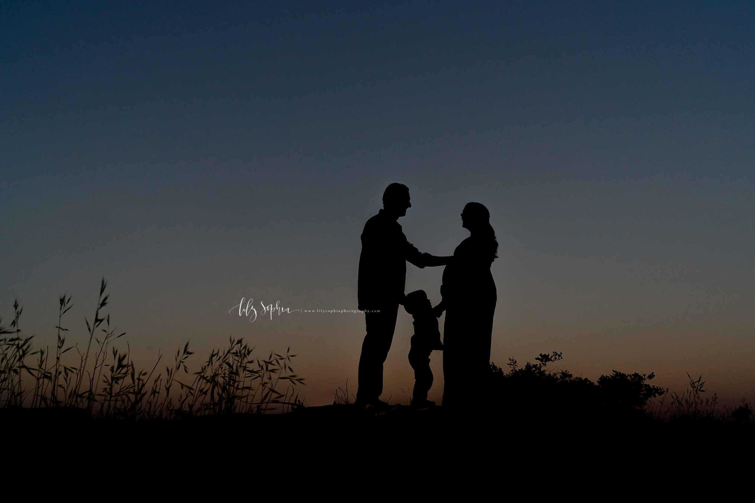  Family of three silhouetted in a maternity photo taken at sunset on a mountain in Atlanta, GA. 