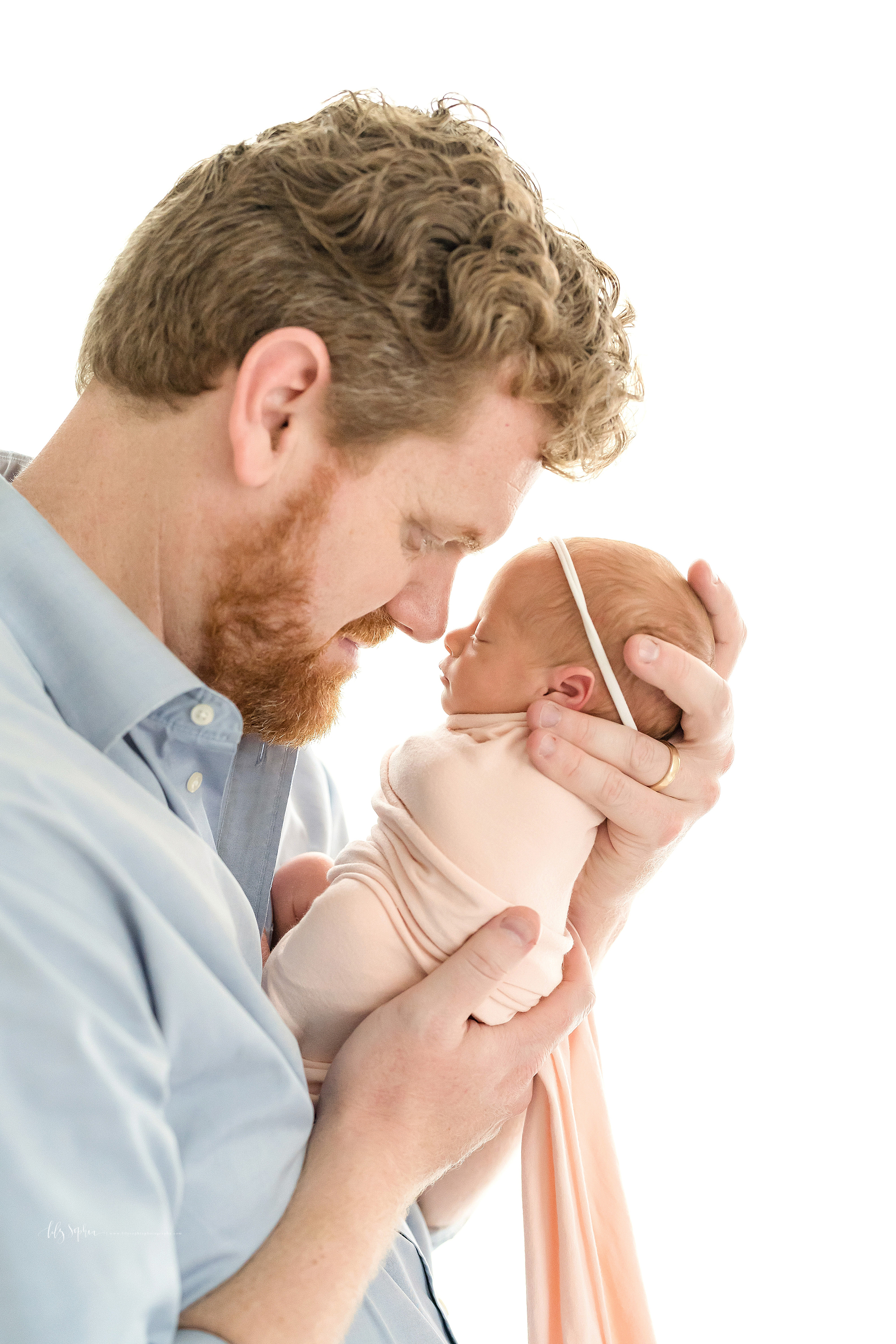  Family photo of dad holding his newborn daughter in a natural light Atlanta studio. 