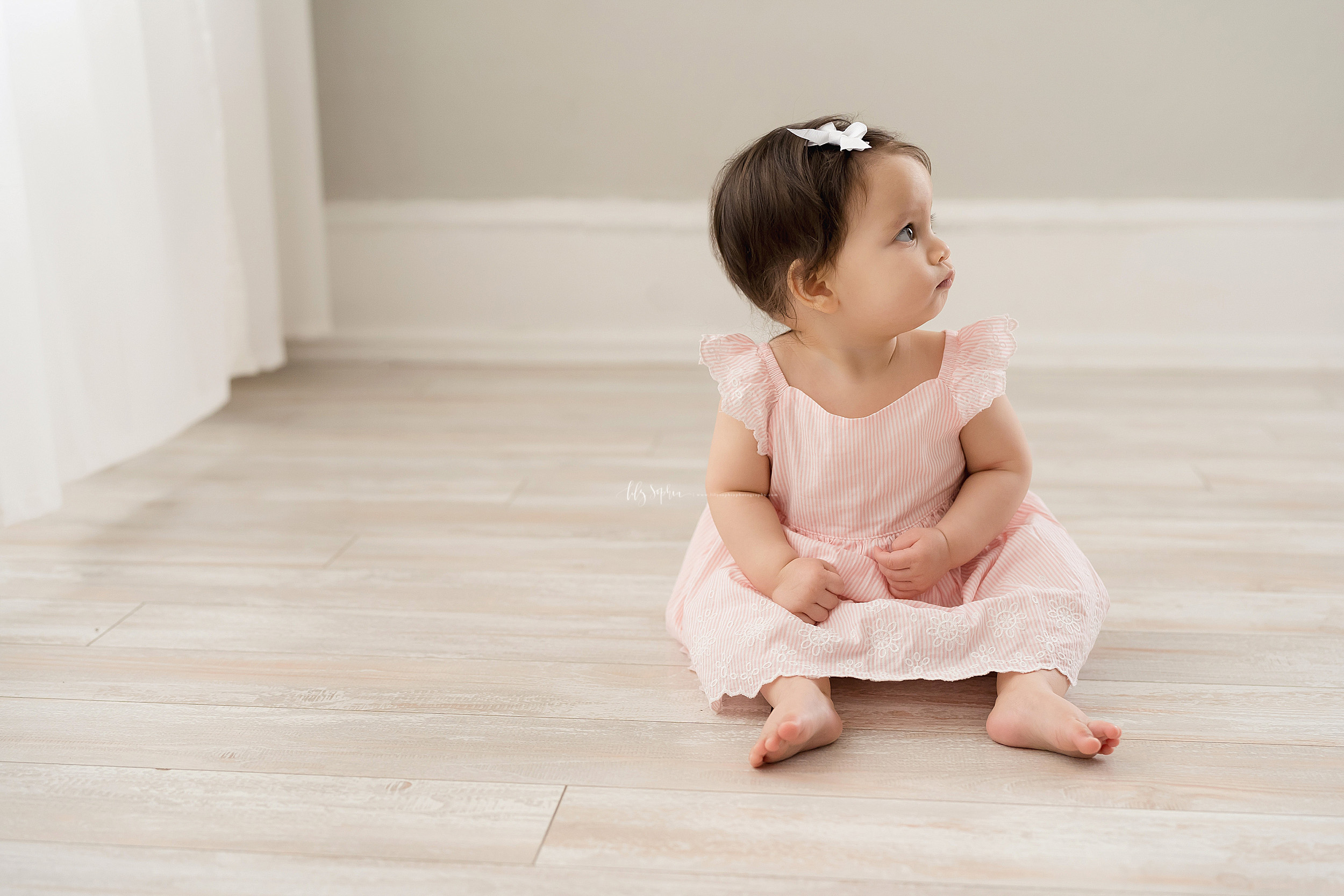  Milestone photo of a serious nine month old as she sits in natural light on the floor of an Atlanta studio. 
