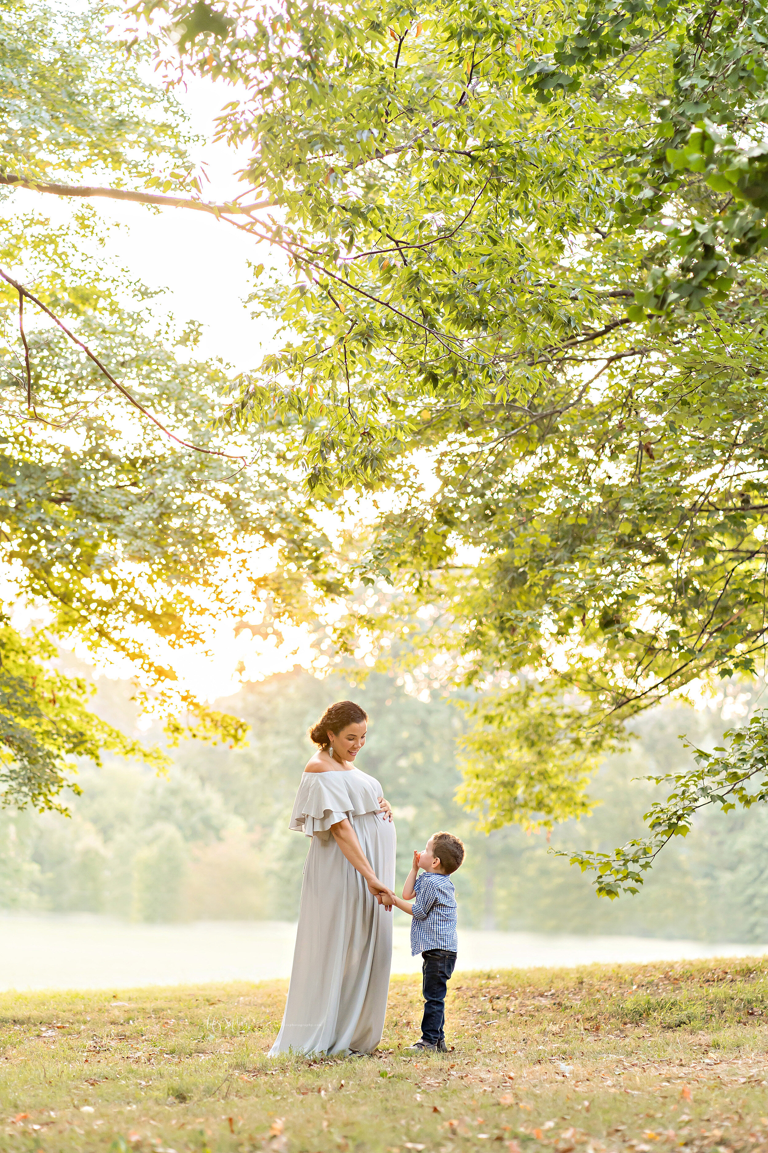  Maternity photo of a mom and her son next to a lake in an Atlanta park at sunset taken in natural light. 