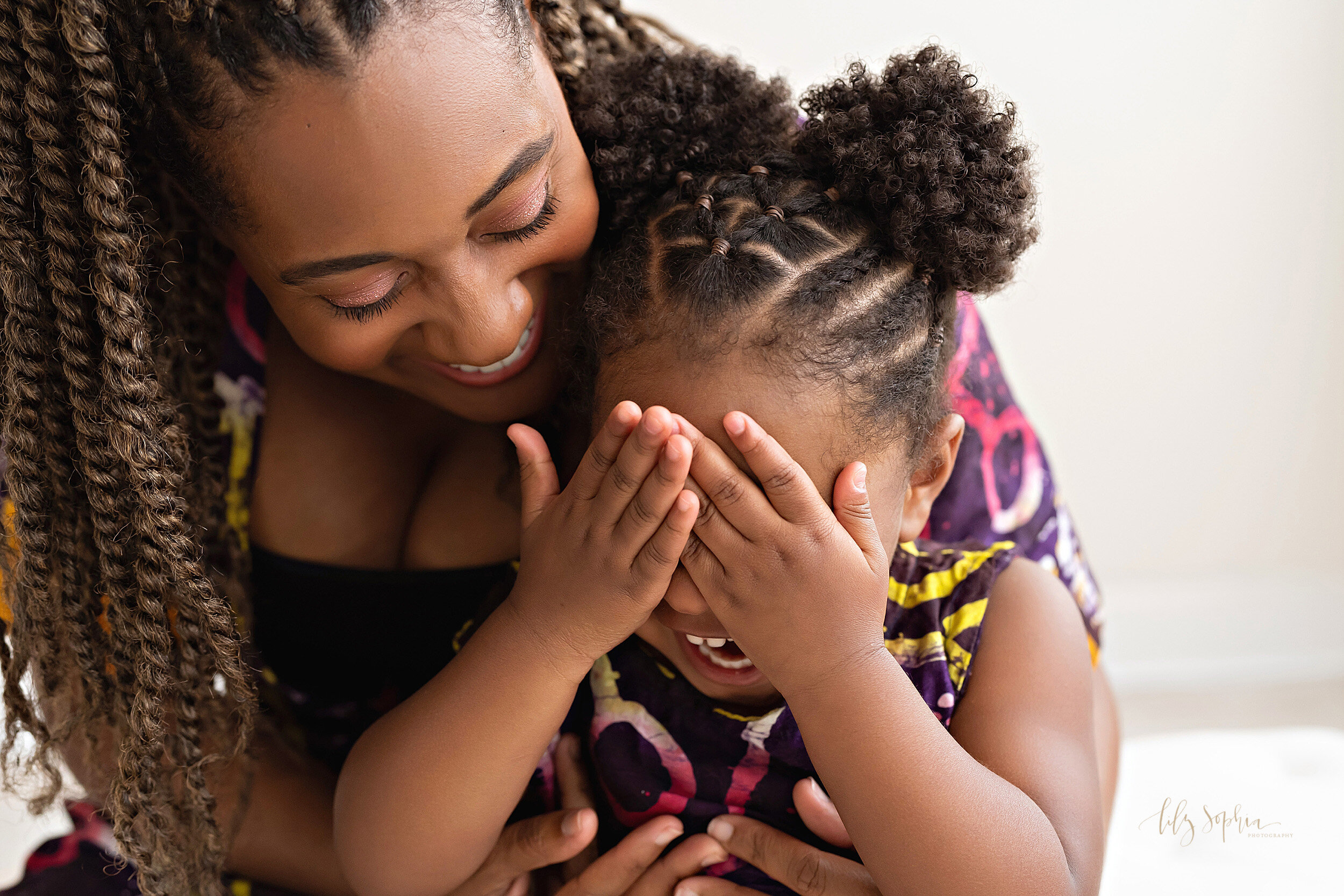  Family photo of an African-American mom and her toddler daughter as they play with one another taken in a natural light studio in the Midtown area of Atlanta, Georgia. 
