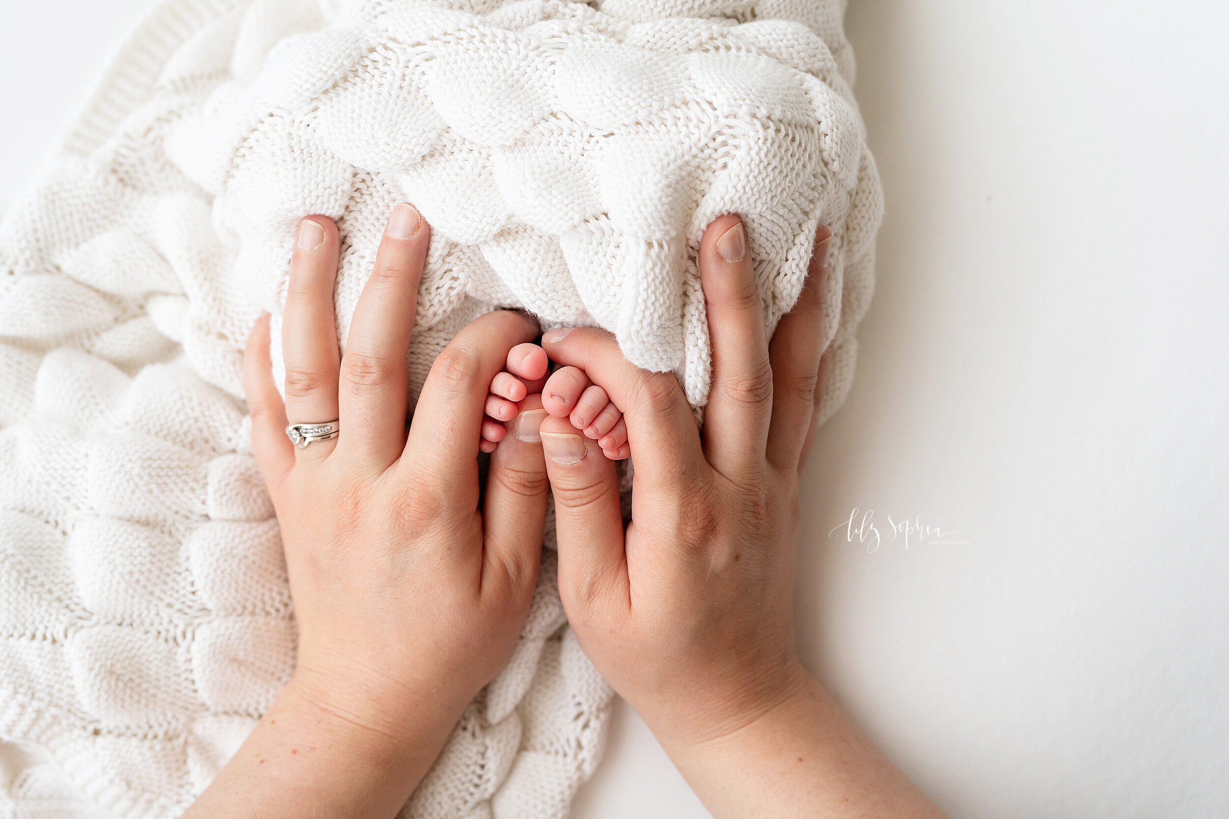  Newborn photo of an infant’s toes being held by her mom to remember how little she was as a newborn taken in a natural light studio in the Ponce City Market in Atlanta. 