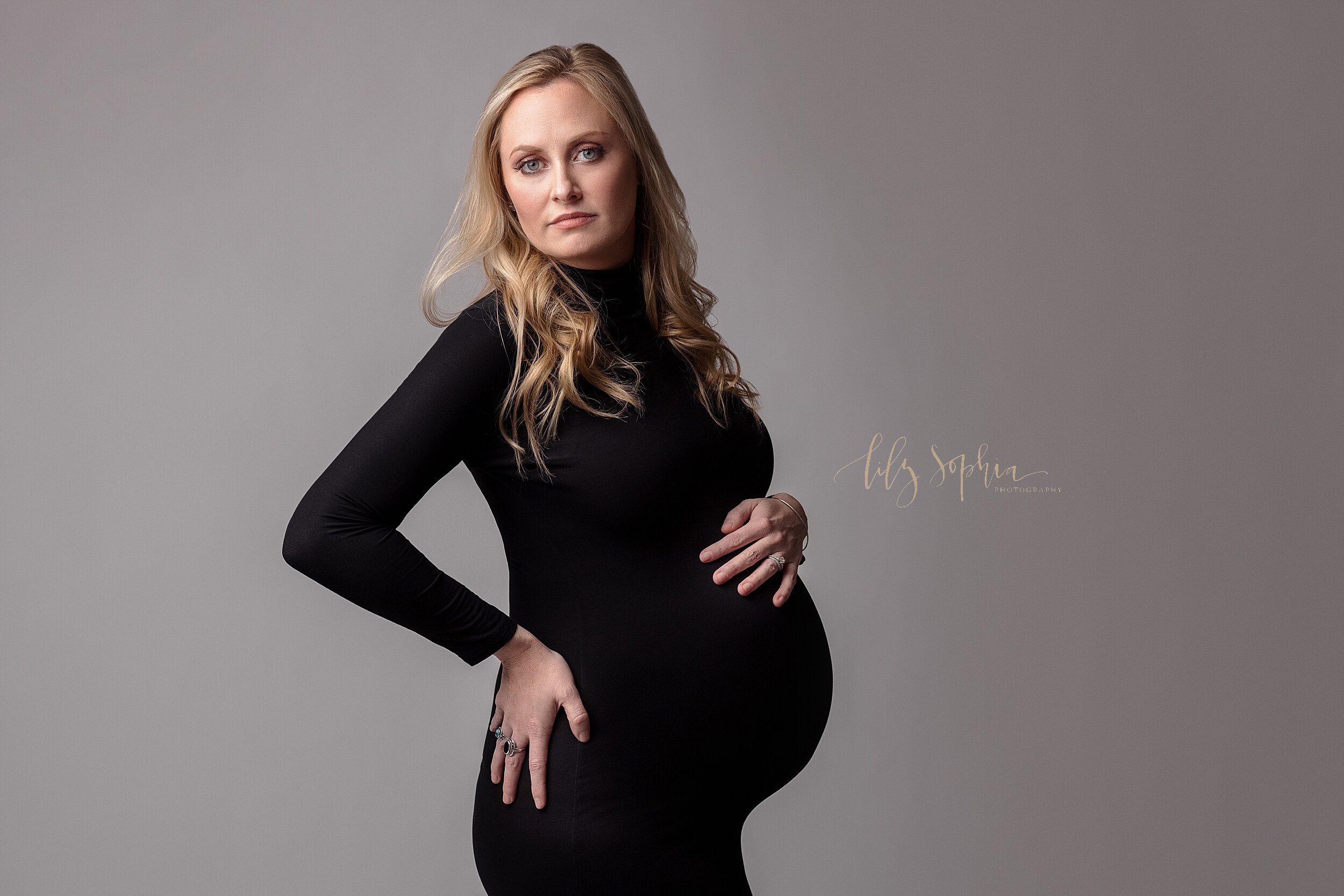  Fine art maternity portrait of beautiful and confident blonde pregnant woman in Atlanta, Georgia wearing long sleeved black turtleneck body con dress.   