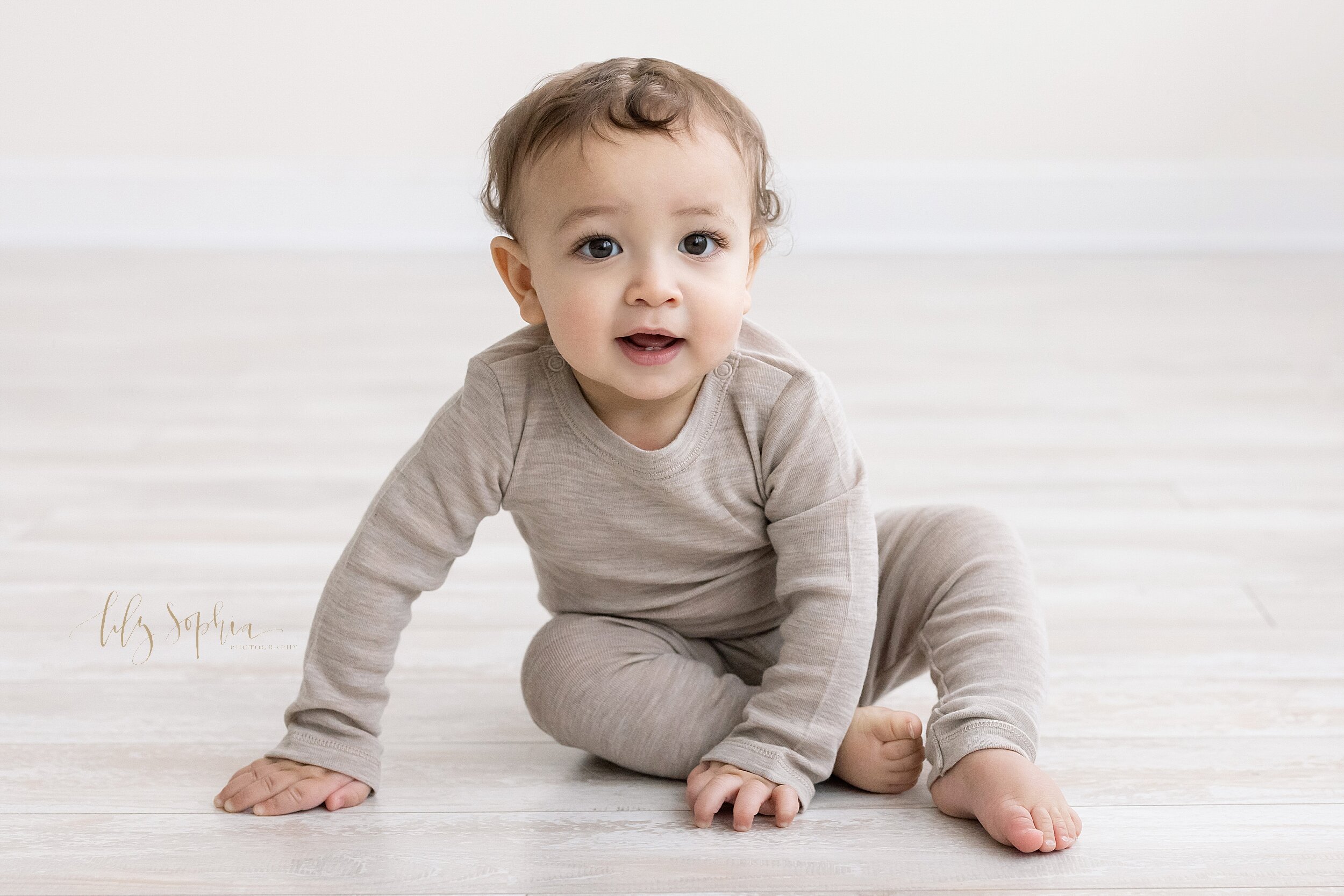  Milestone photo of a seven month old little boy as he sits on the floor of a studio in natural light in the Buckhead area of Atlanta and is getting ready to crawl. 