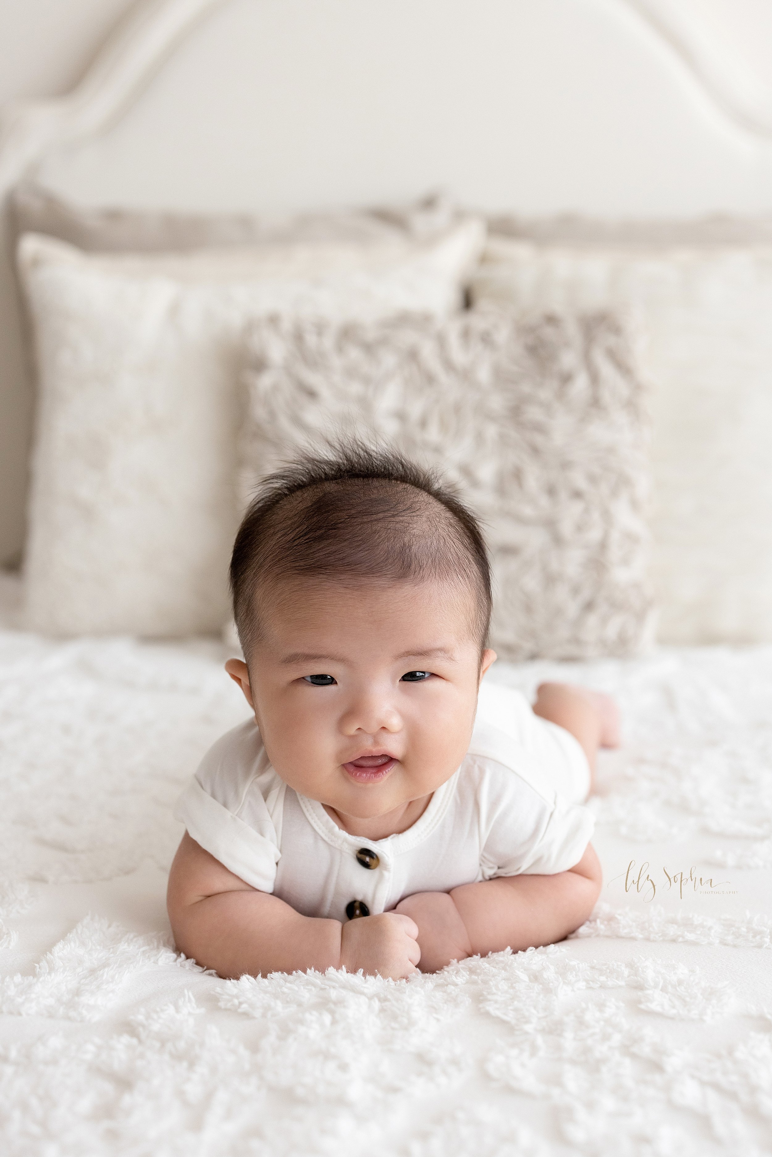  Milestone photo session of an Asian infant boy as he lies on his stomach on a bed taken in a natural light studio near Decatur in Atlanta, Georgia. 