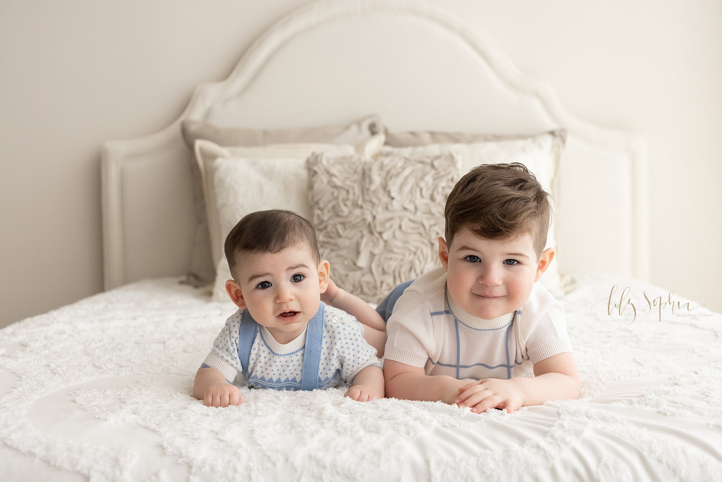  Family portrait of a six month old boy and his brother as the two lie on their stomachs on a bed in a natural light studio near Oakhurst in Atlanta. 