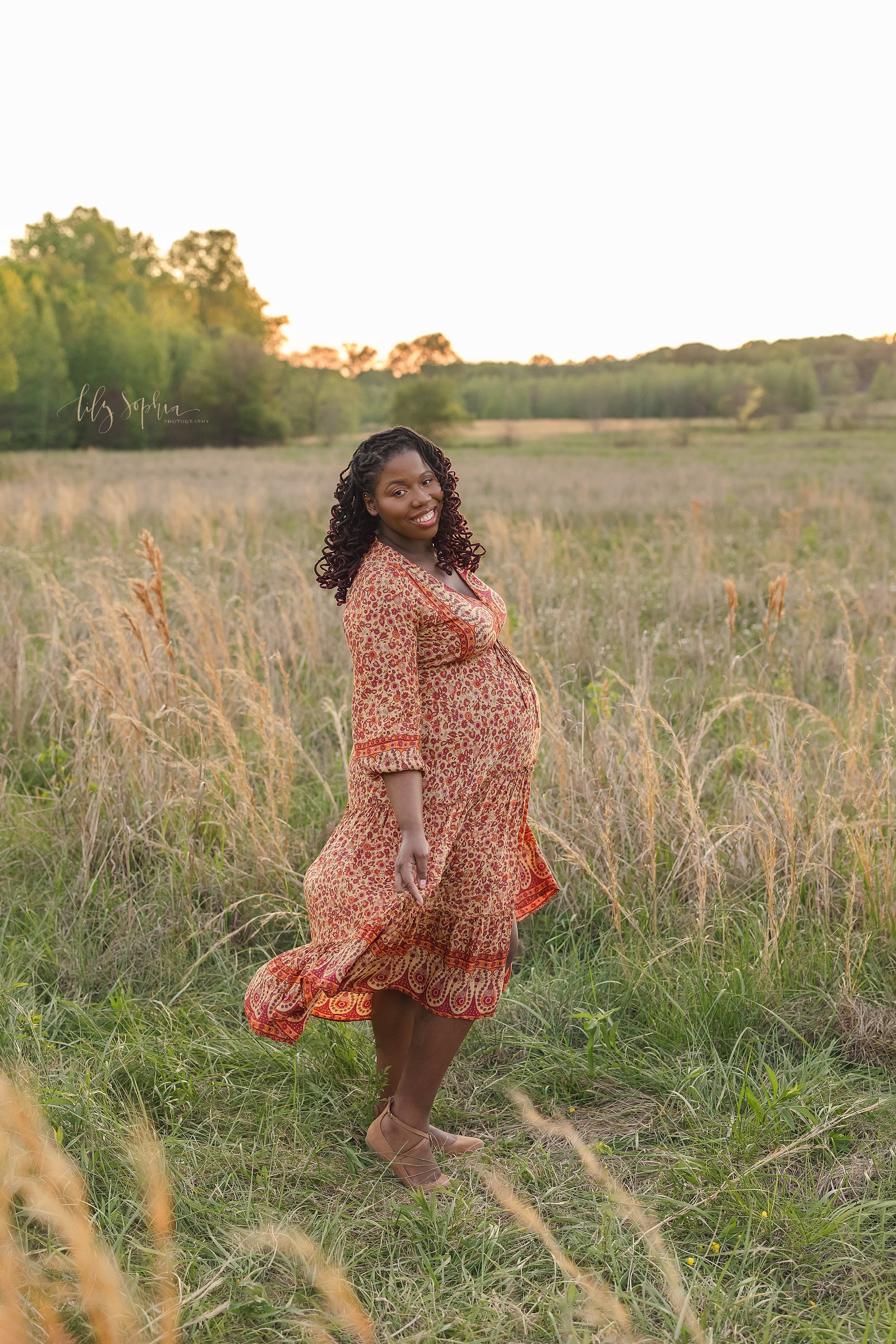  Maternity portrait of an African-American expectant mother with flowing black curls as she twirls in a field at sunset near Atlanta. 