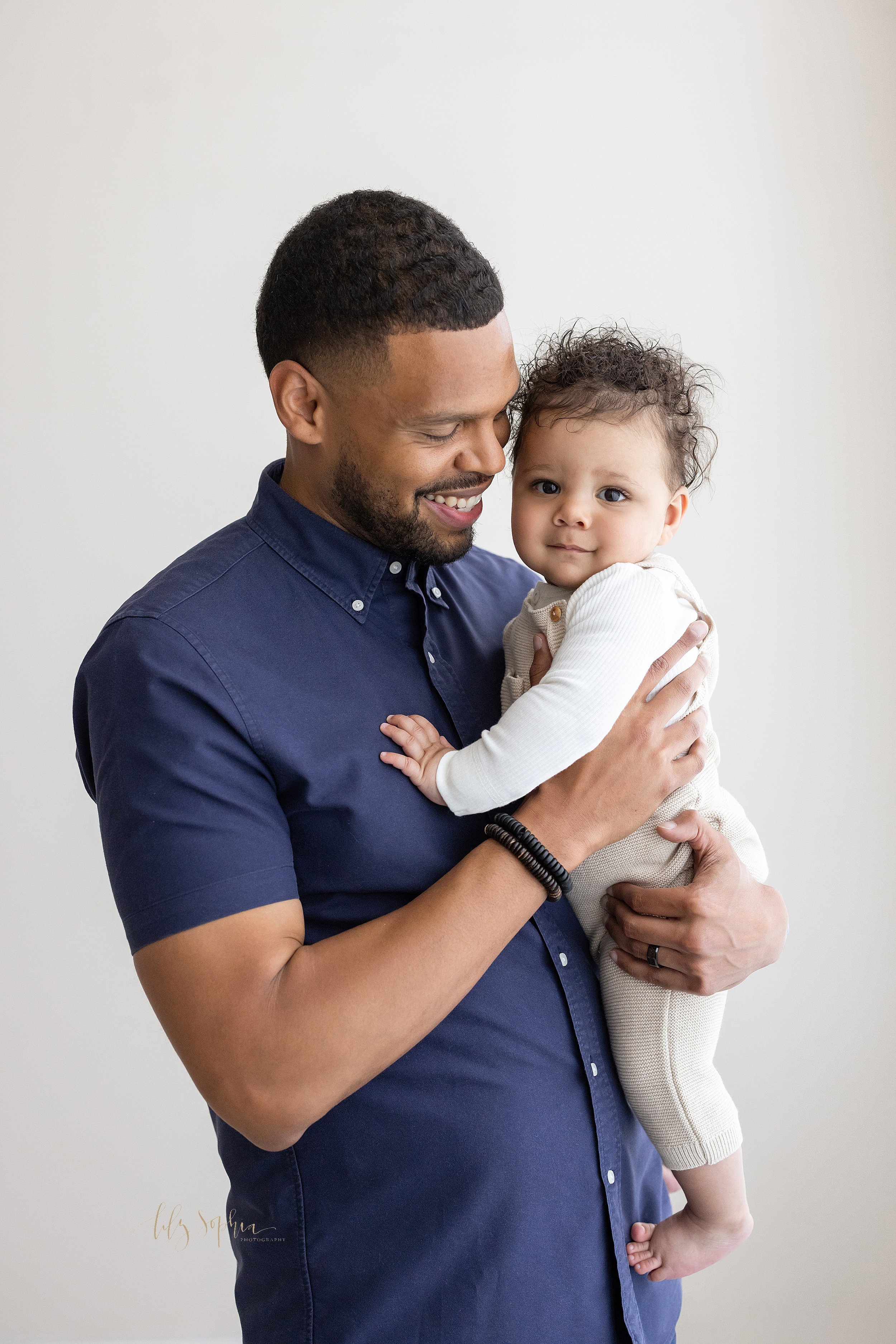  Family photo of a father holding his seven month old son in a natural light studio in Ponce City Market in Atlanta. 