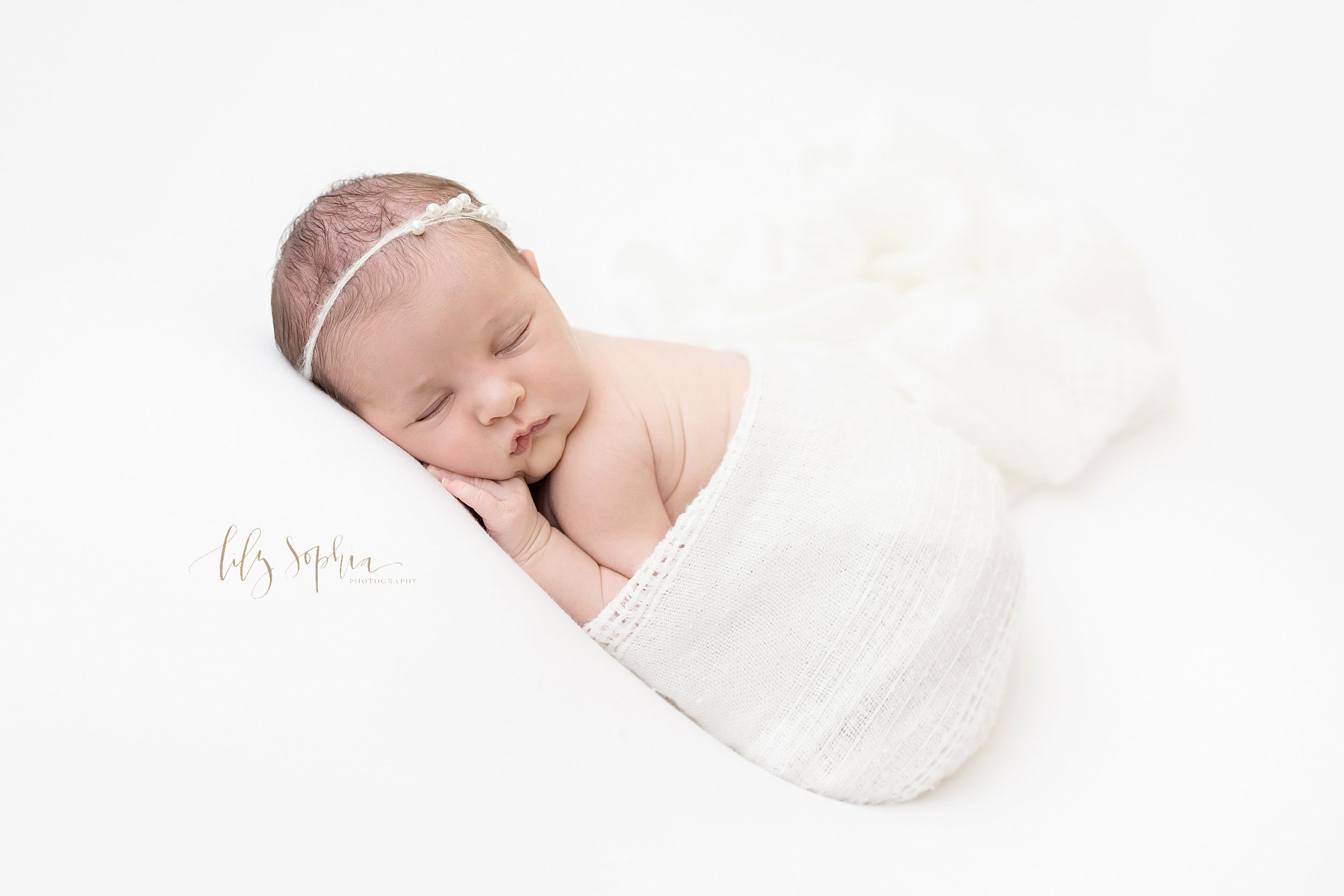  Newborn portrait of a slumbering infant girl sitting in a knitted blanket with her wrinkly back showing taken in a studio near Alpharetta in Atlanta that uses natural lighting. 