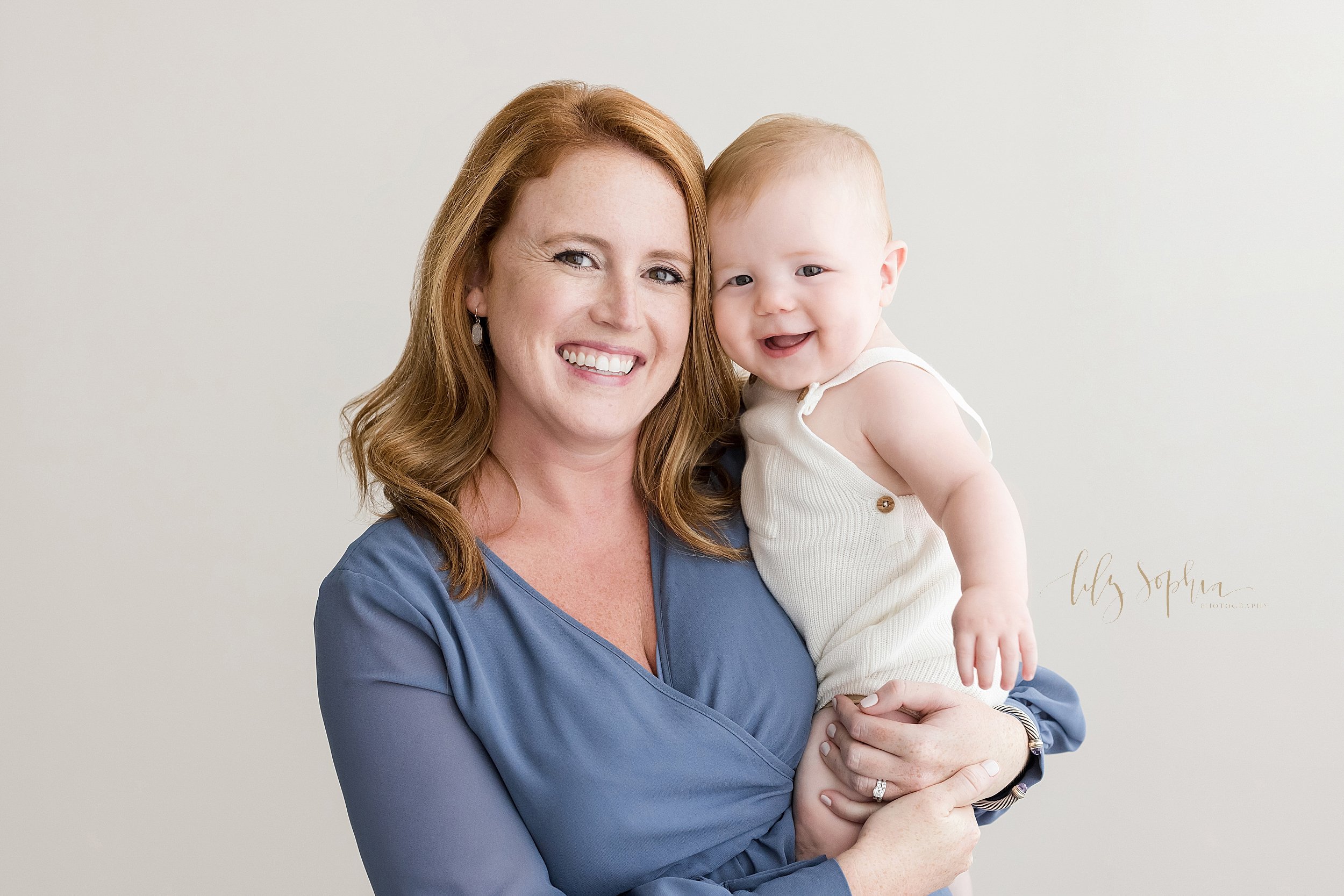  Family photograph of a mother holding her smiling six month old red-headed baby boy in a studio near Old Fourth Ward in Atlanta that uses natural light. 