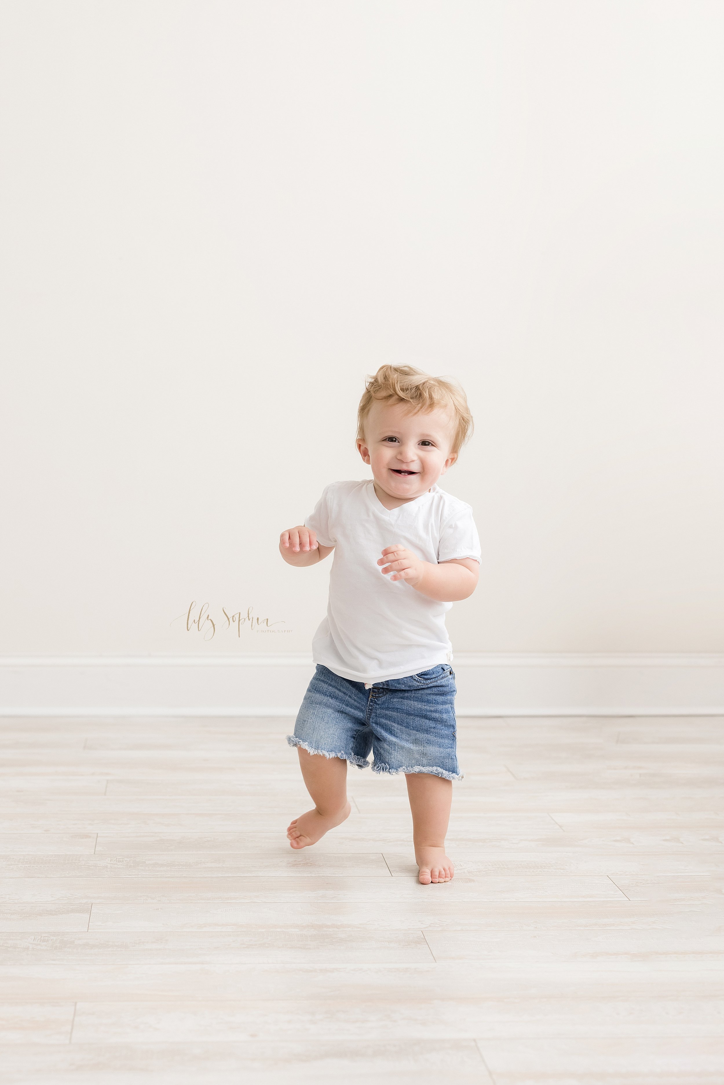 First birthday photograph of a one year old little boy as he runs in a studio using natural light near Alpharetta in Atlanta. 