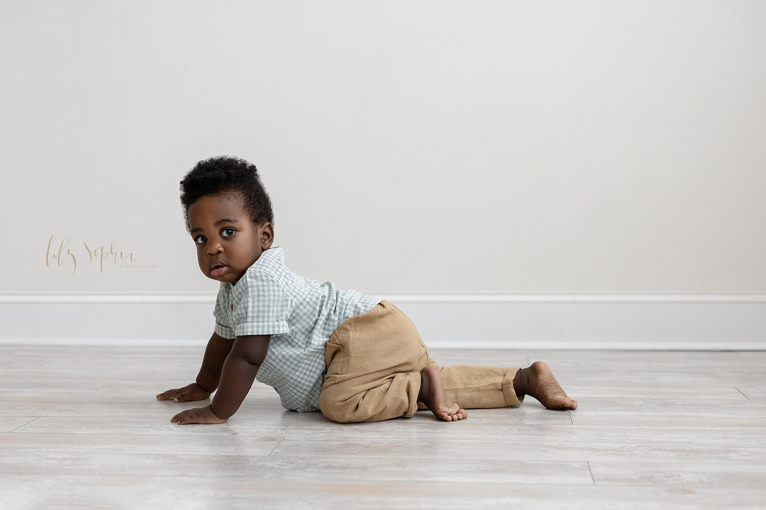  First birthday portrait of a one year old black boy as he crawls in a natural light studio near Cummings in Atlanta. 