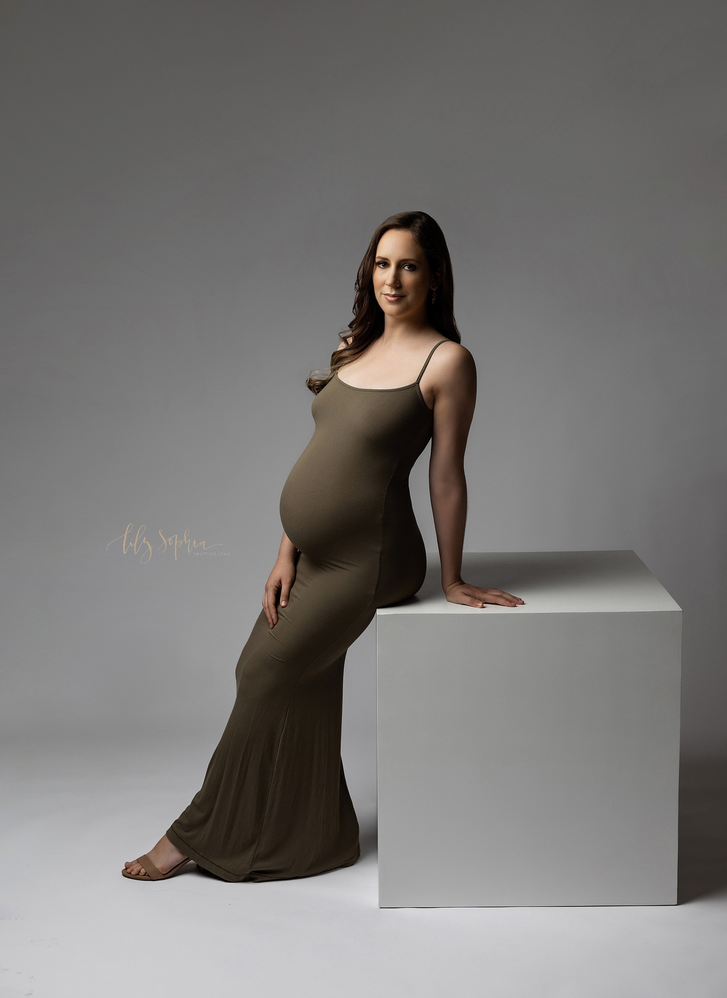  Modern maternity pictures of a pregnant mother as she stands and leans against a large white cube taken in a studio near Kirkwood in Atlanta. 