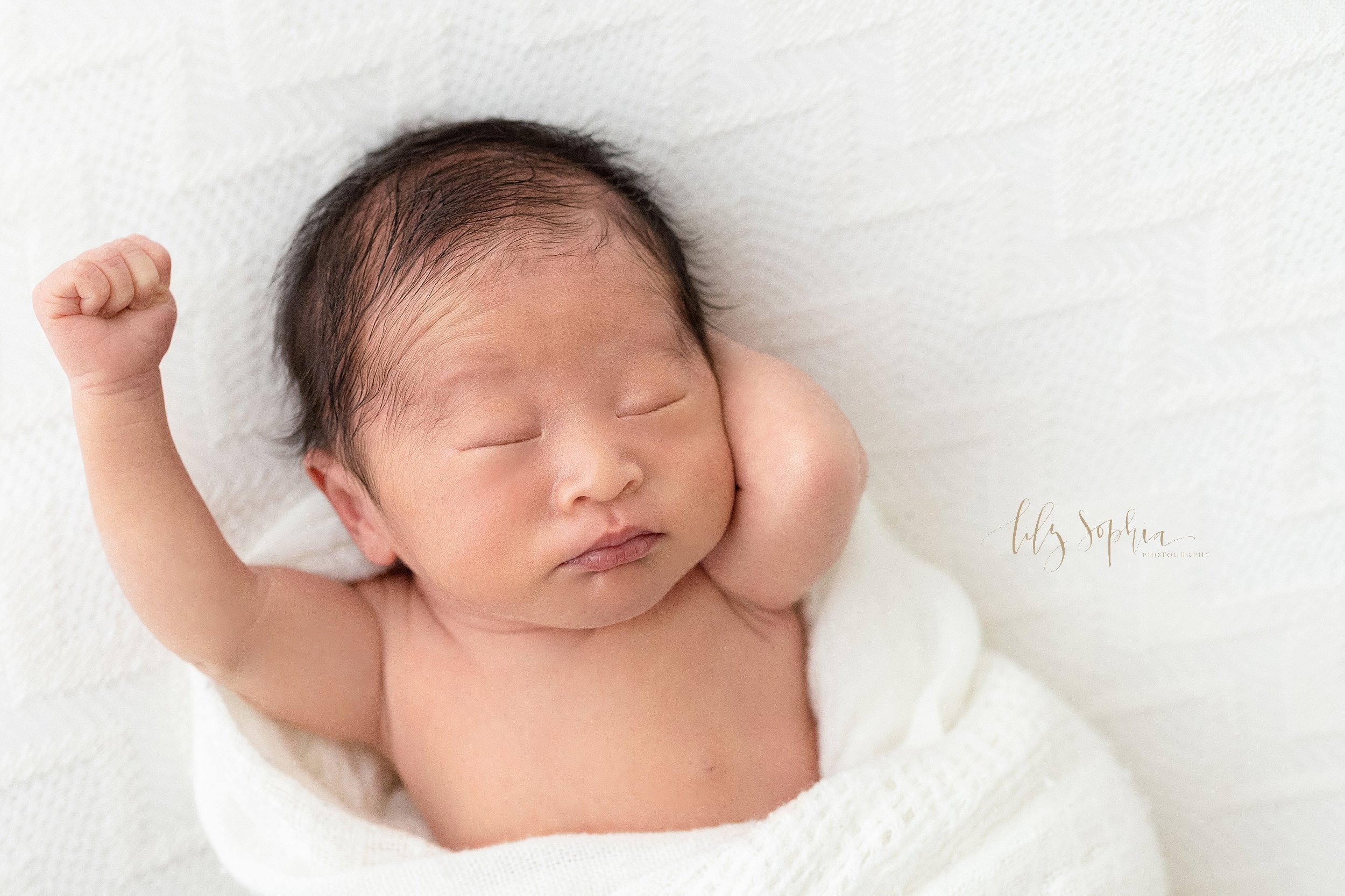  Newborn picture of an Asian baby boy as he stretches to wake up taken in a natural light studio near Oakhurst in Atlanta. 