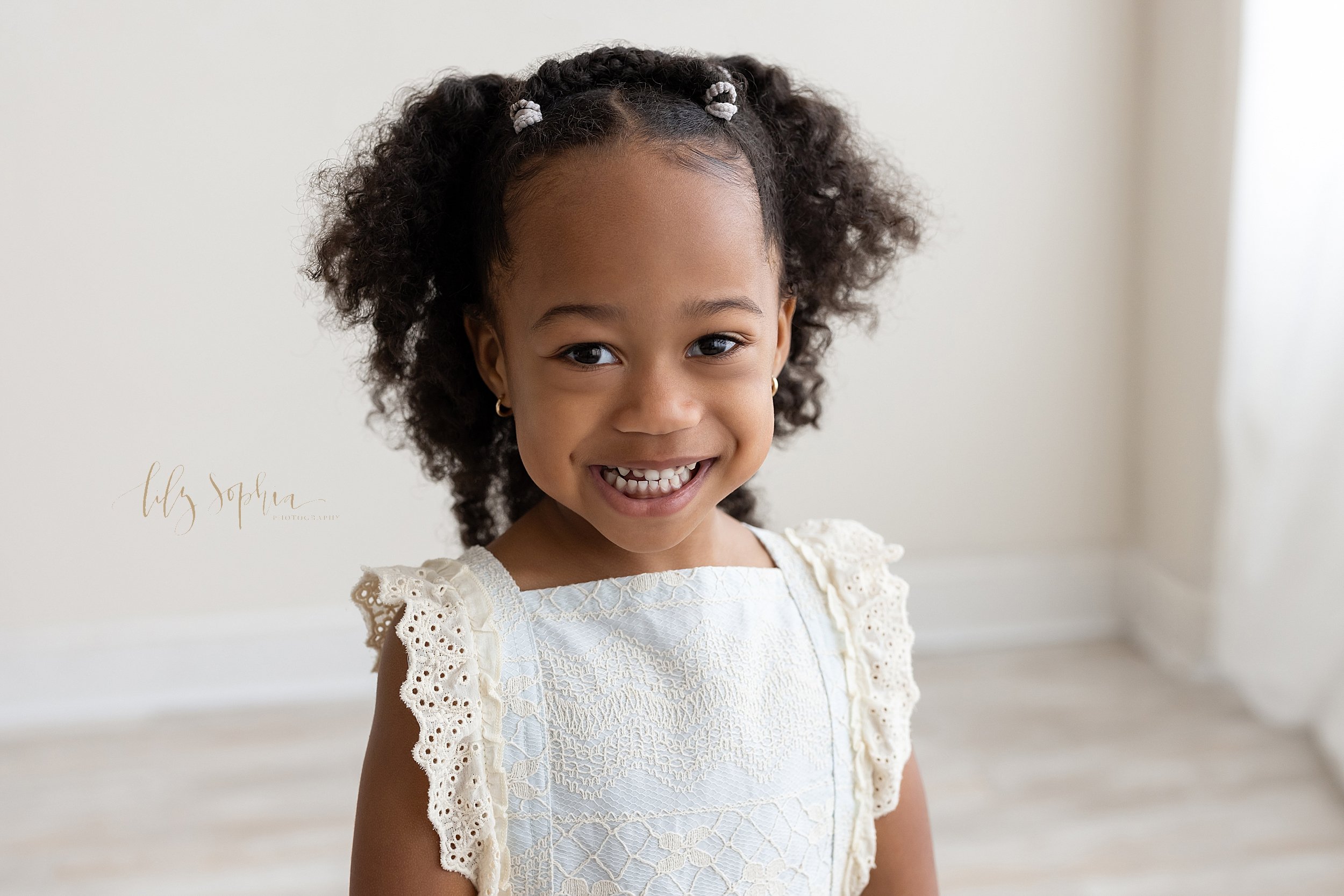  Family photo of a happy young African-American girl as she stands smiling in a natural light studio near Morningside in Atlanta. 