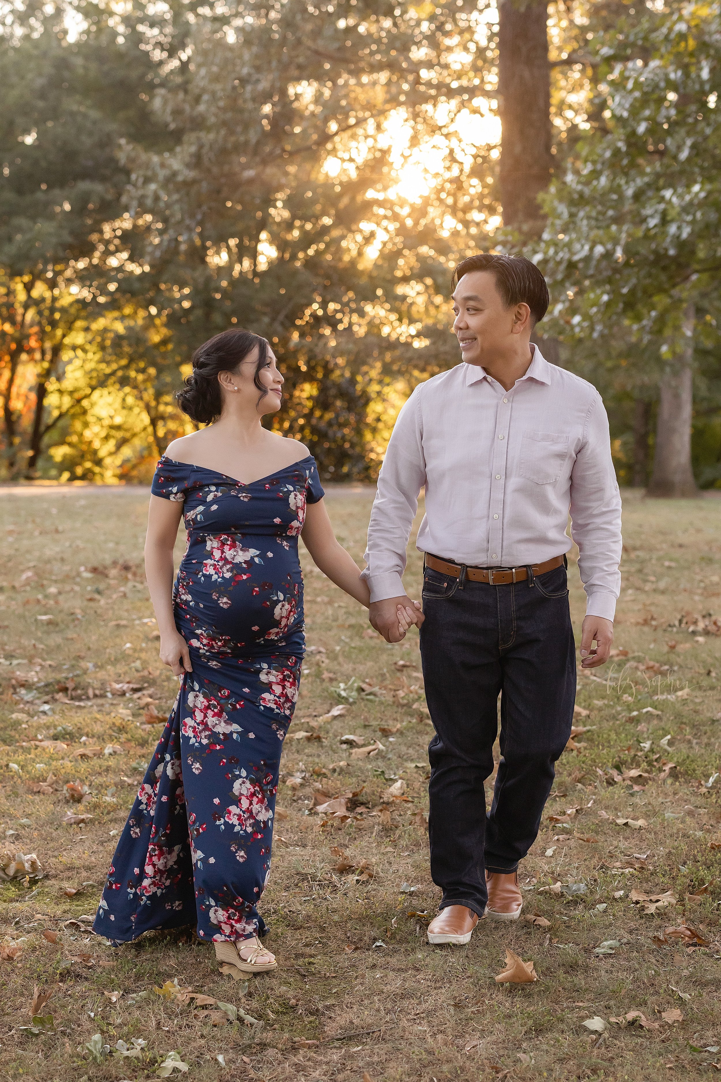  Maternity photo session of an Asian expectant couple as they walk hand-in-hand through a park in Atlanta at sunset. 