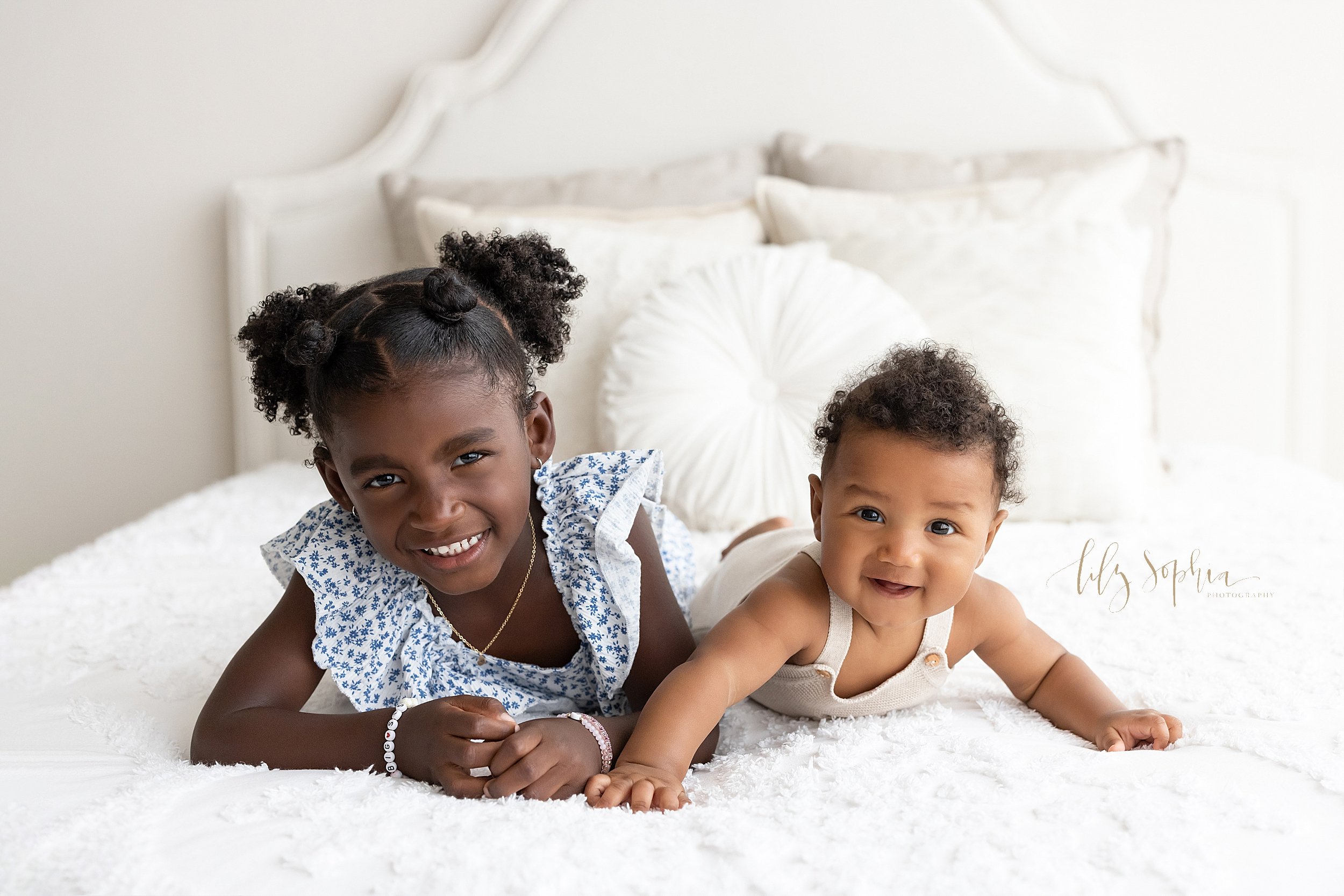  Family photo of African-American siblings lying on their stomachs atop a bed taken in a studio near Virginia Highlands in Atlanta that uses natural light. 