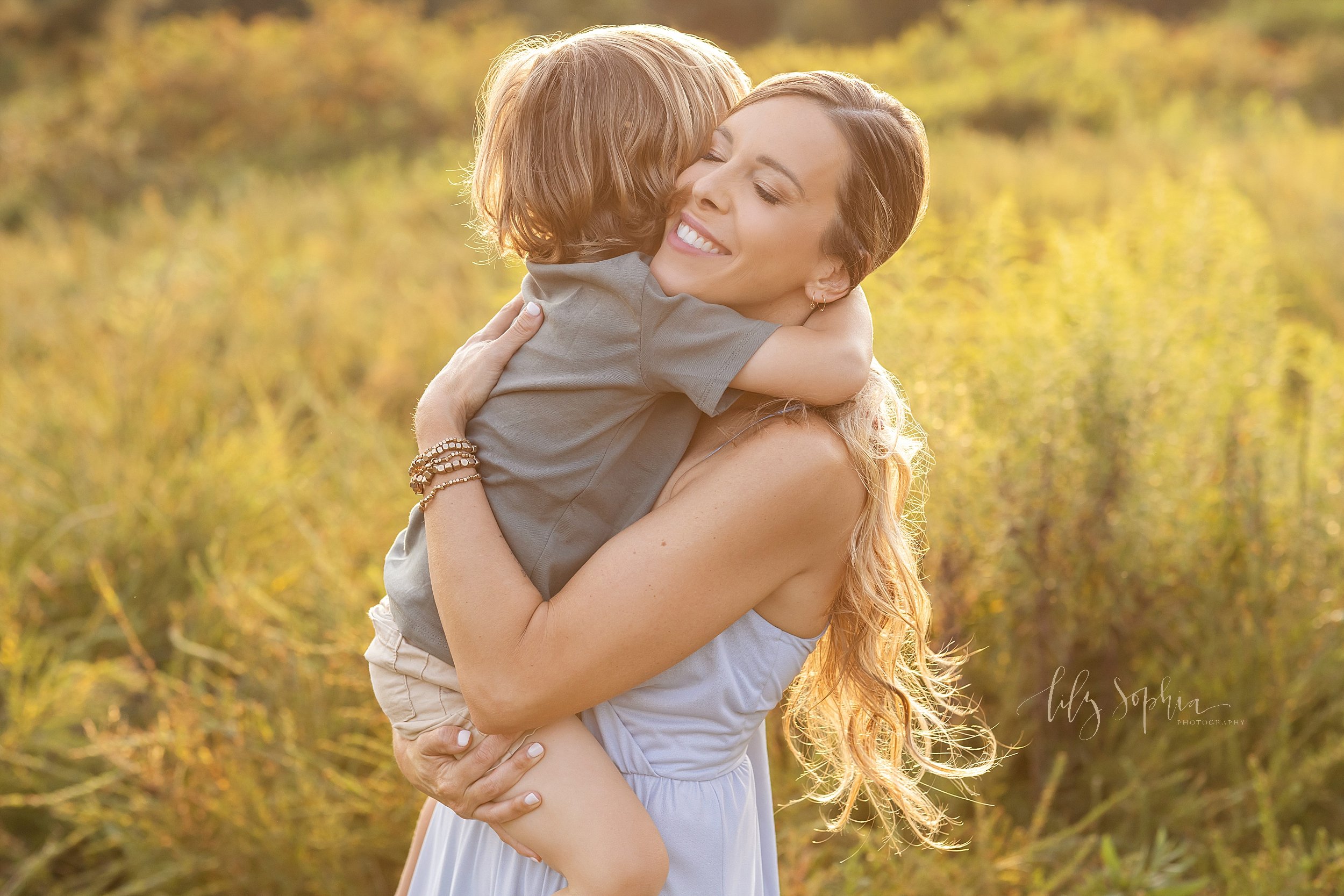  Family picture of a mother holding her young son while she still can and treasuring this moment taken at sunset in a field near Atlanta, Georgia. 