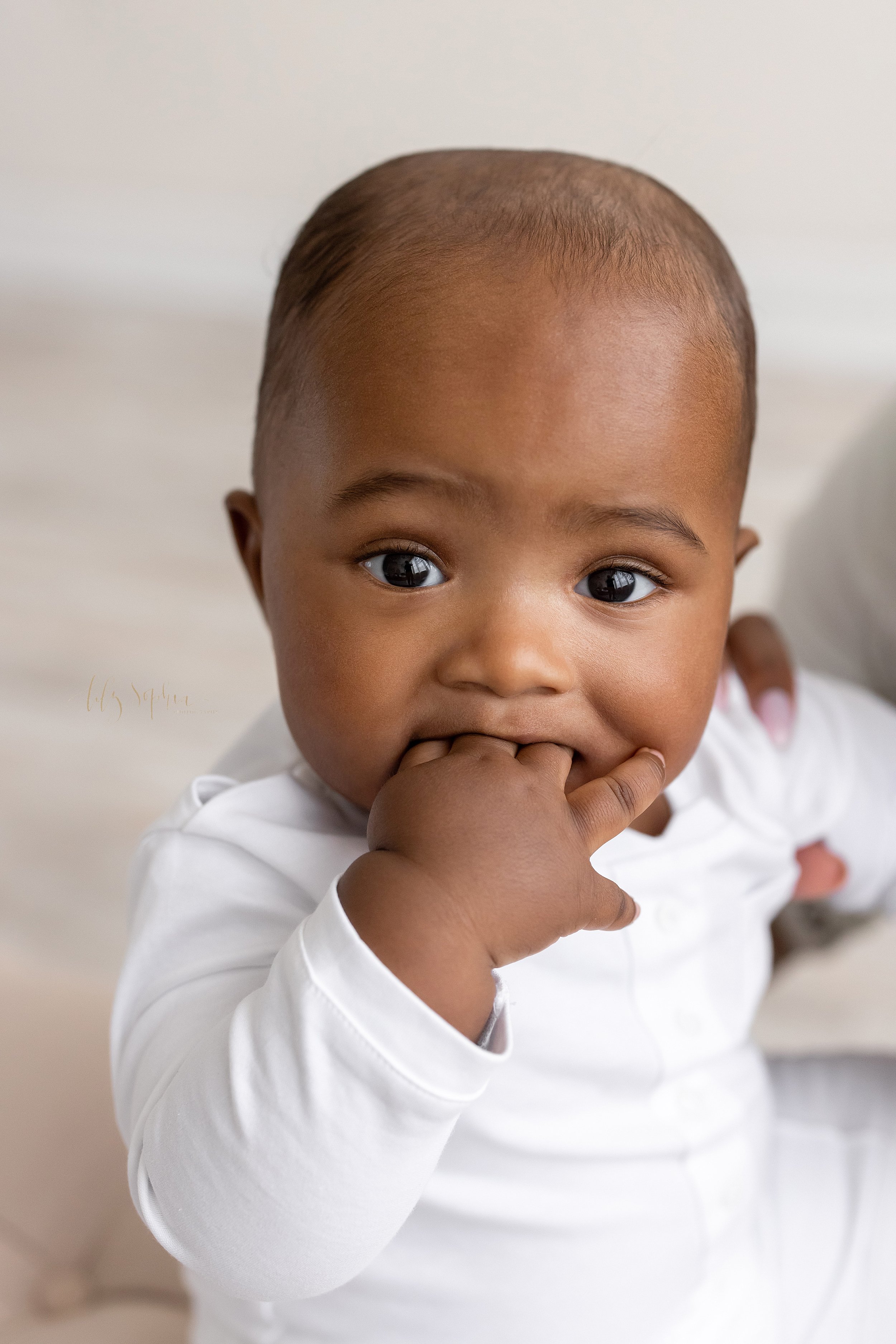  Baby close-up photo of an African-American baby boy with his fingers of his right hand shoved in his mouth taken in a studio near Smyrna in Atlanta that uses natural light. 