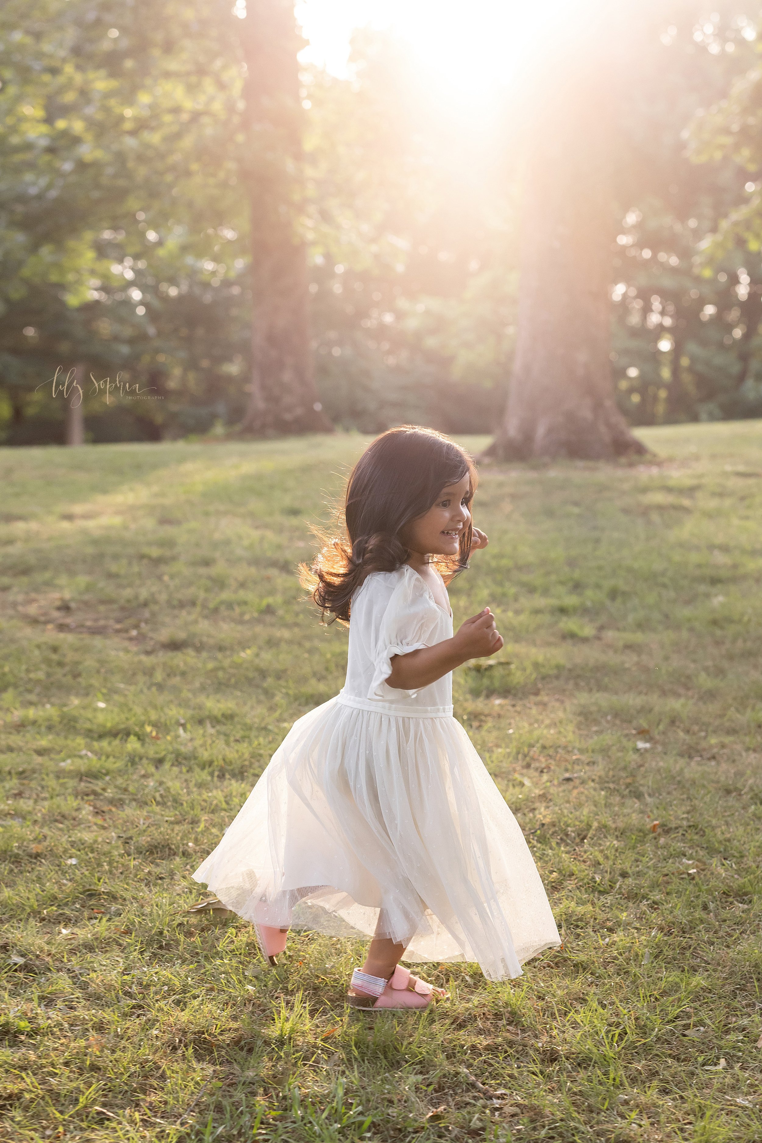  Family picture of a young Indian girl running through an Atlanta park at sunset. 