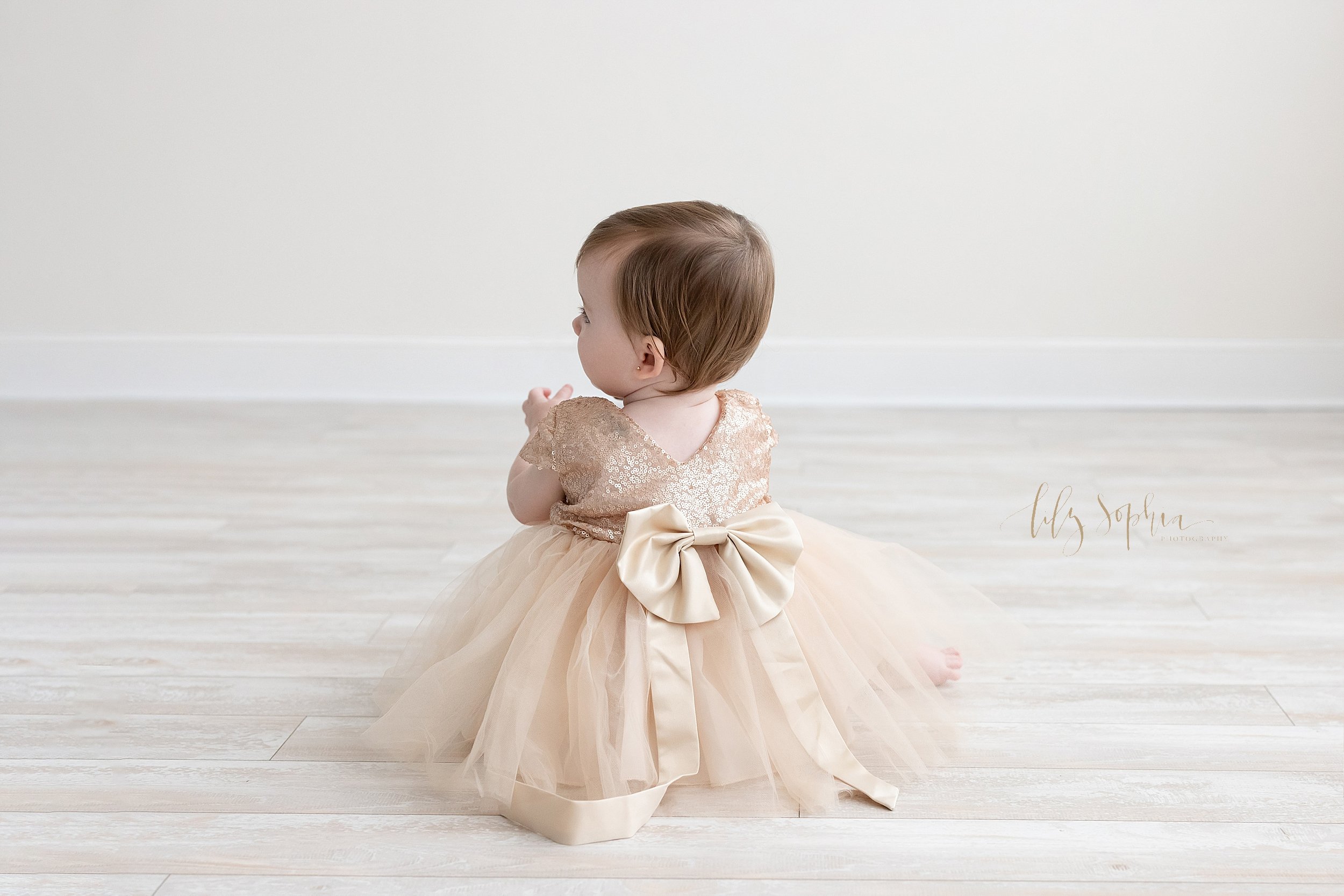 First birthday portrait of a one year old baby girl as she sits on the floor of a studio near Smyrna in Atlanta that uses natural light. 