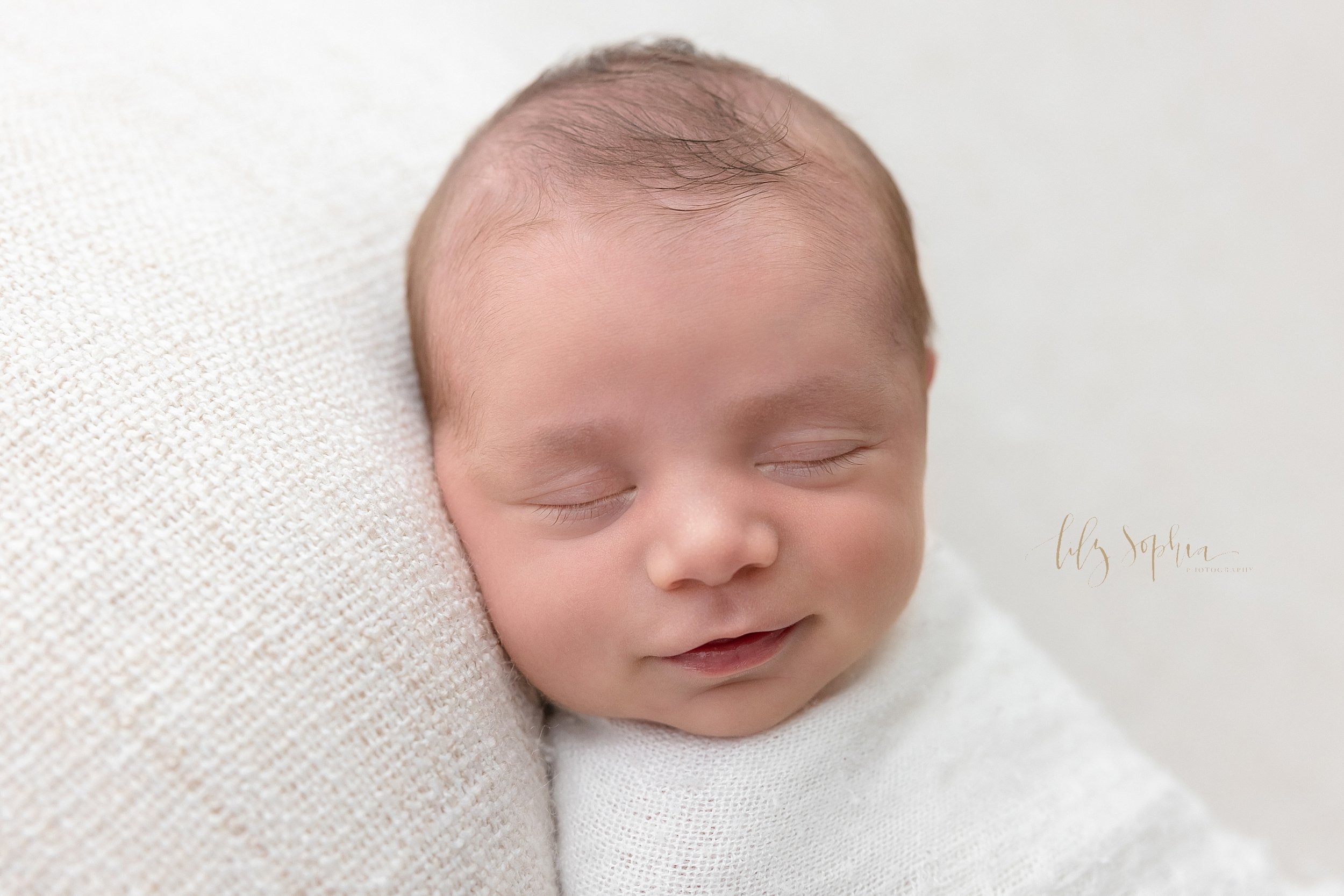 Newborn photo session in a studio using natural light of a newborn baby boy as he smiles in his sleep taken in Ponce City Market in Atlanta, Georgia. 