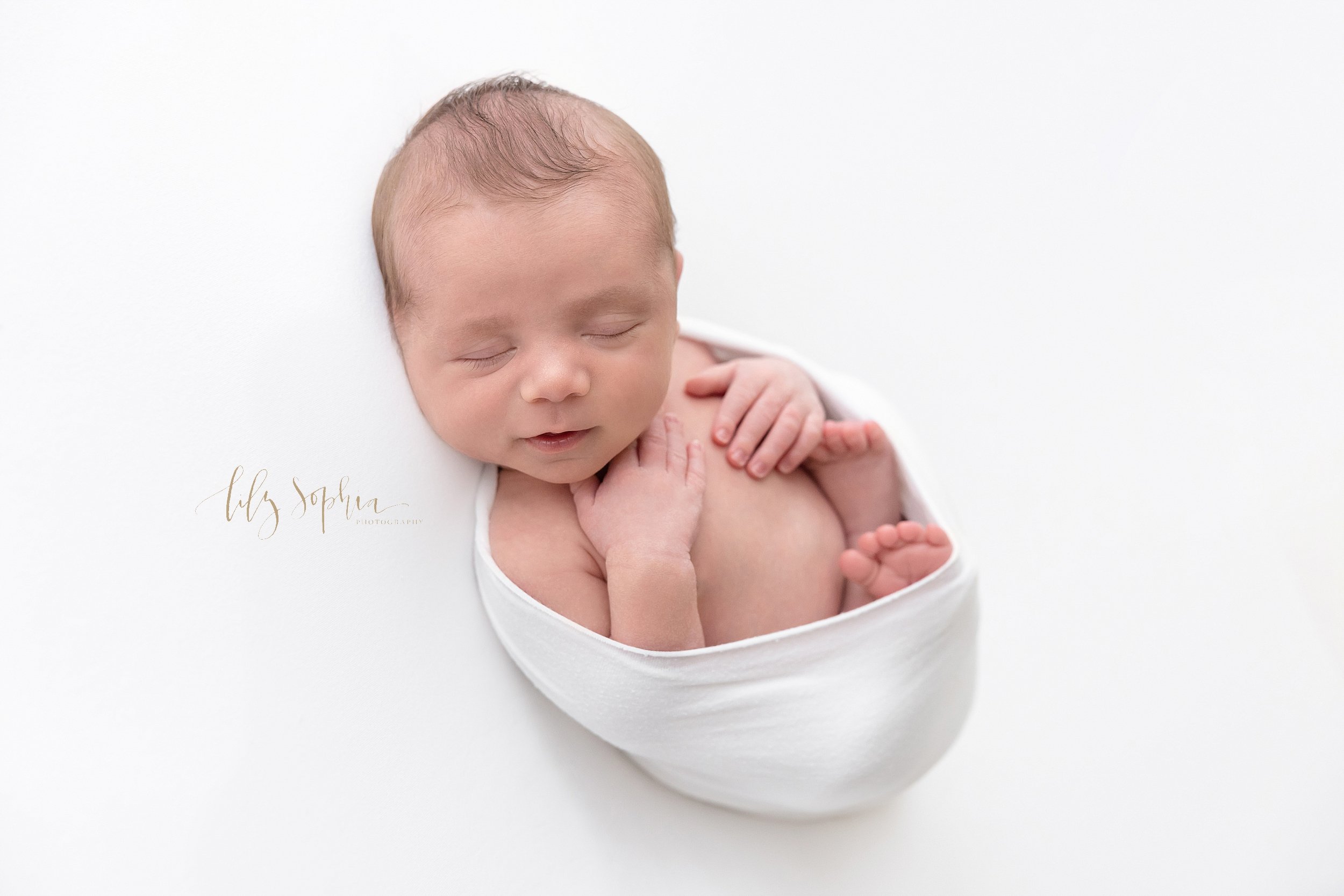  Newborn photo session of a newborn baby boy nestled in a stretchy swaddle taken in a natural light studio near Cumming in Atlanta. 