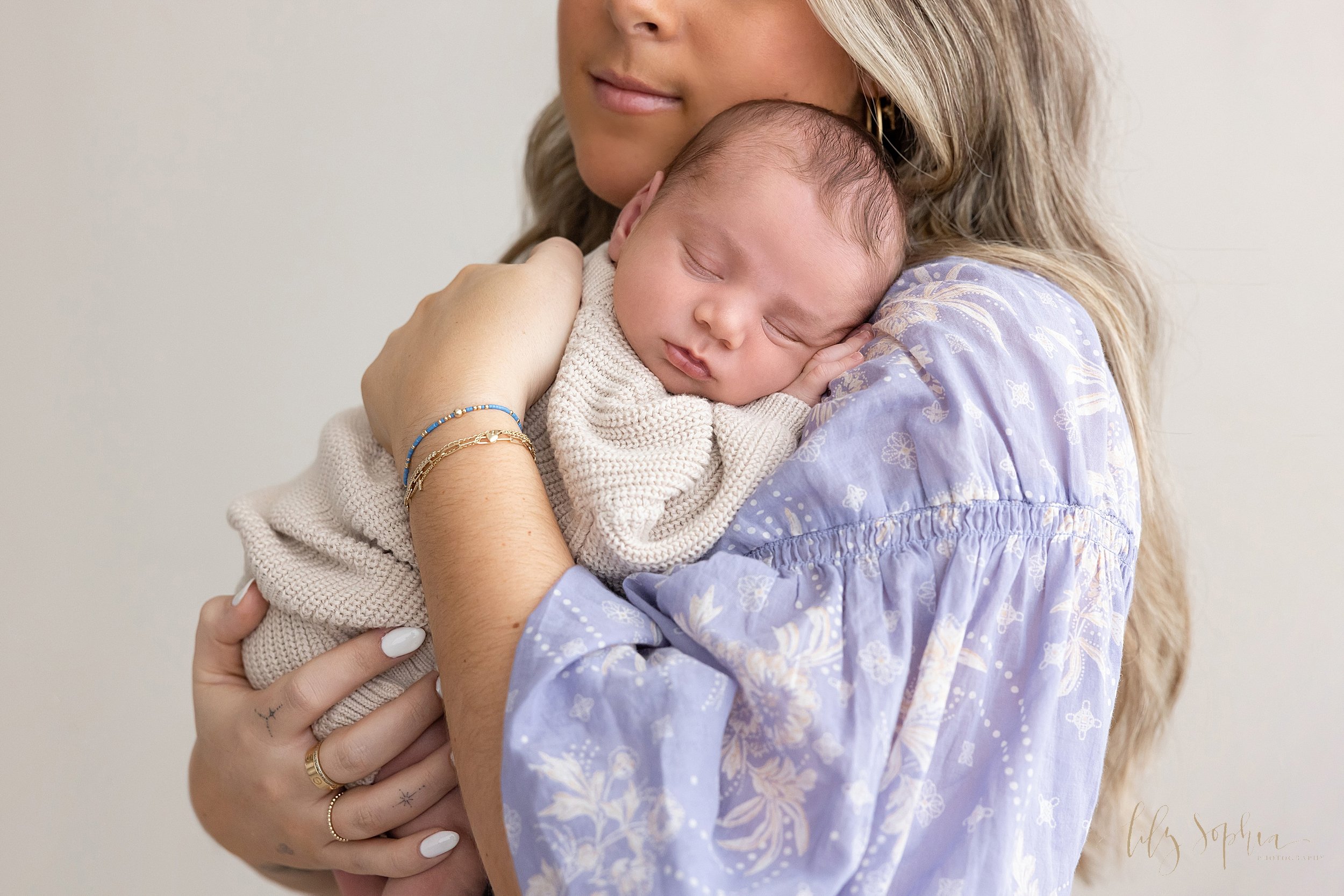  Newborn picture of a sleeping newborn baby boy as he is held by his mother as she stands in a photography studio near Roswell in Atlanta that uses natural light. 