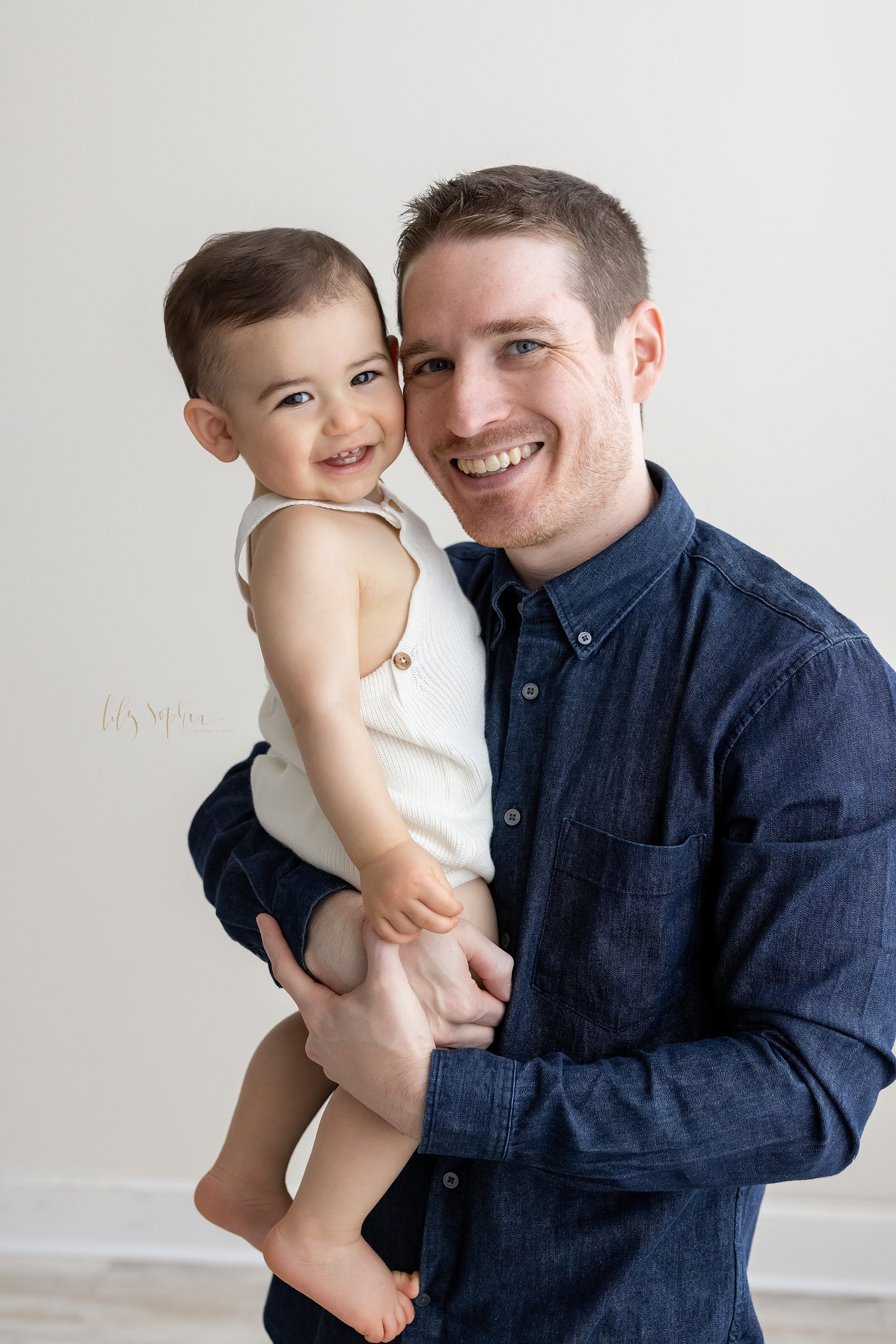  First birthday picture of a father holding his one year old son taken in natural light near Vinings in Atlanta in a studio. 
