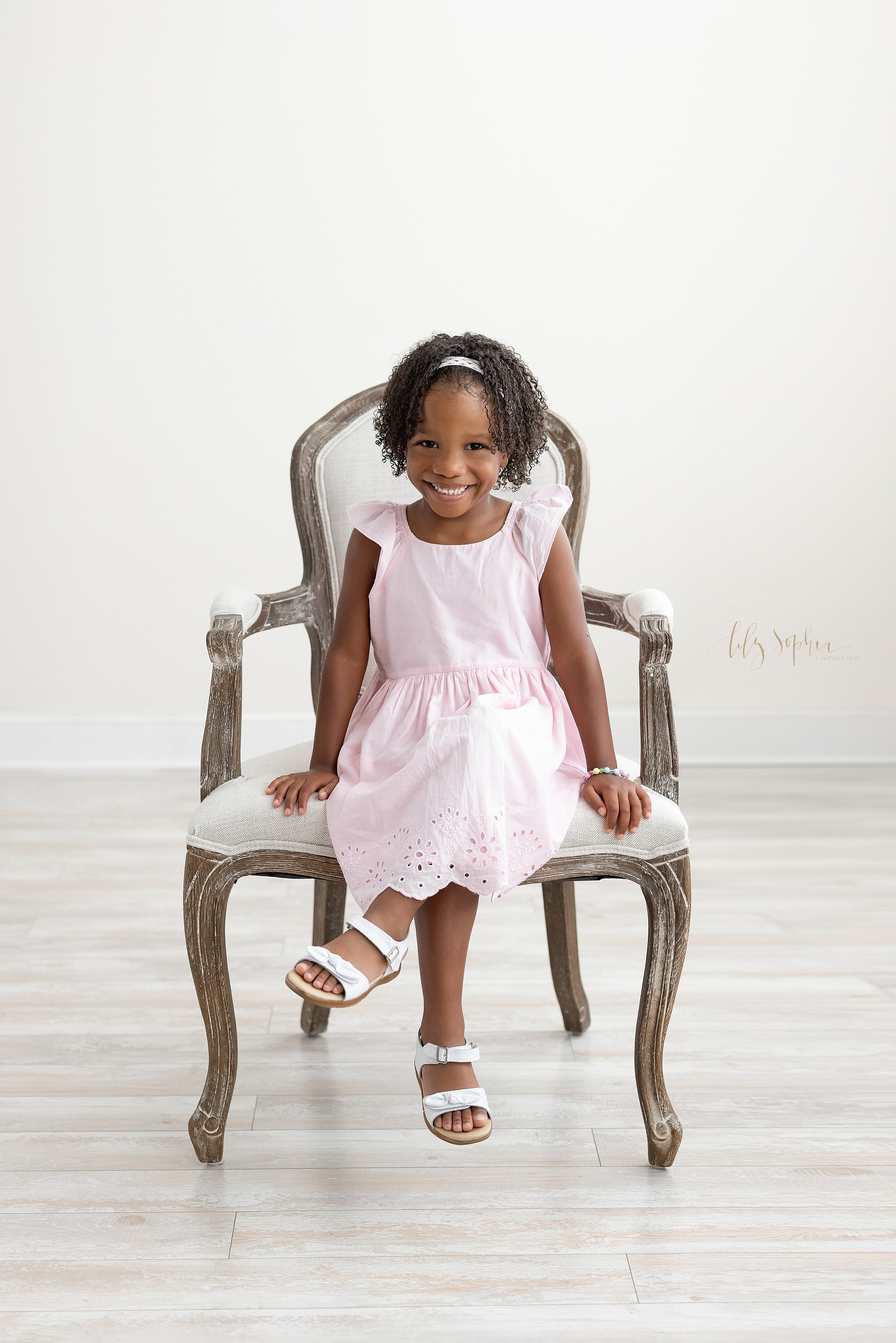  Family portrait of a young African-American girl as she sits with her left leg crossed over her right in an armchair taken in a studio near Kirkwood in Atlanta in natural light. 