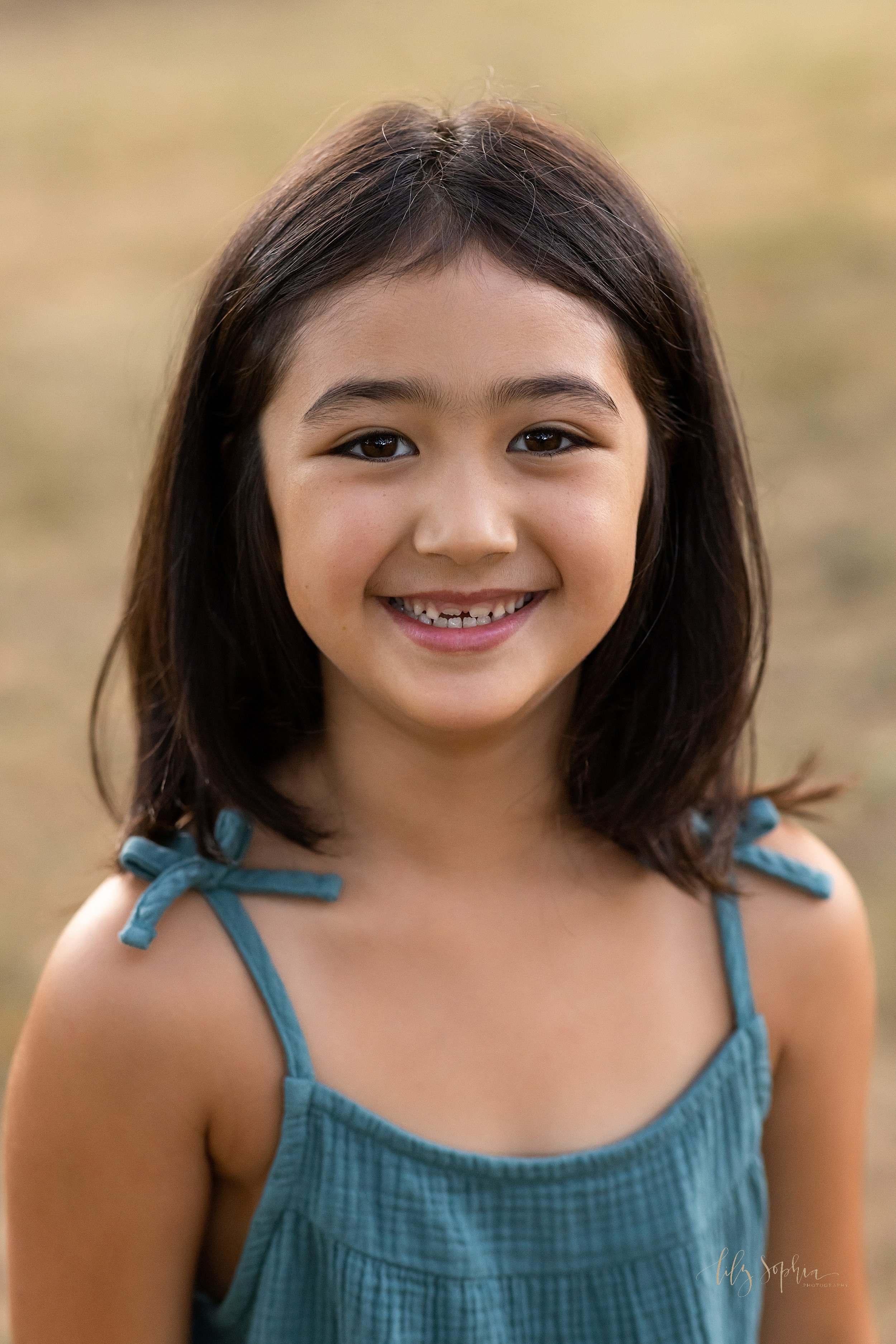  Close-up portrait of an Asian girl as she smiles showing her permanent teeth growing in taken in a park near Atlanta, Georgia at sunset. 