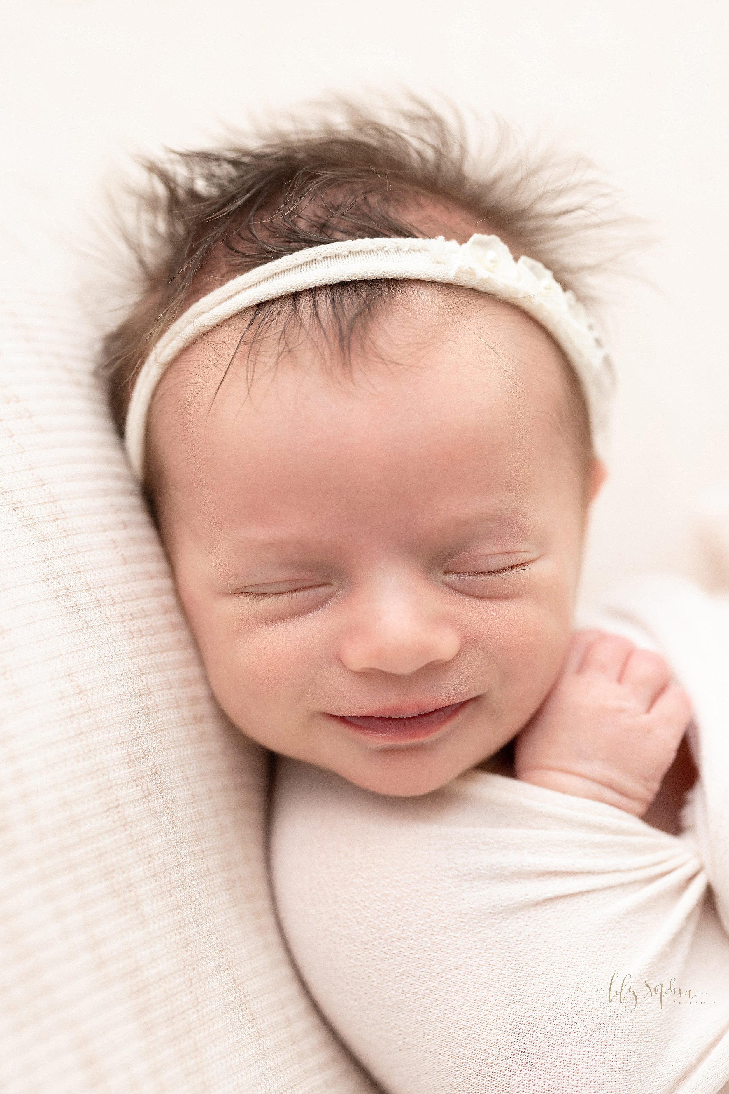  Newborn portrait of a baby girl as she smiles in her sleep taken in Ponce City Market in Atlanta, Georgia in the natural light Lily Sophia Photography Studio. 