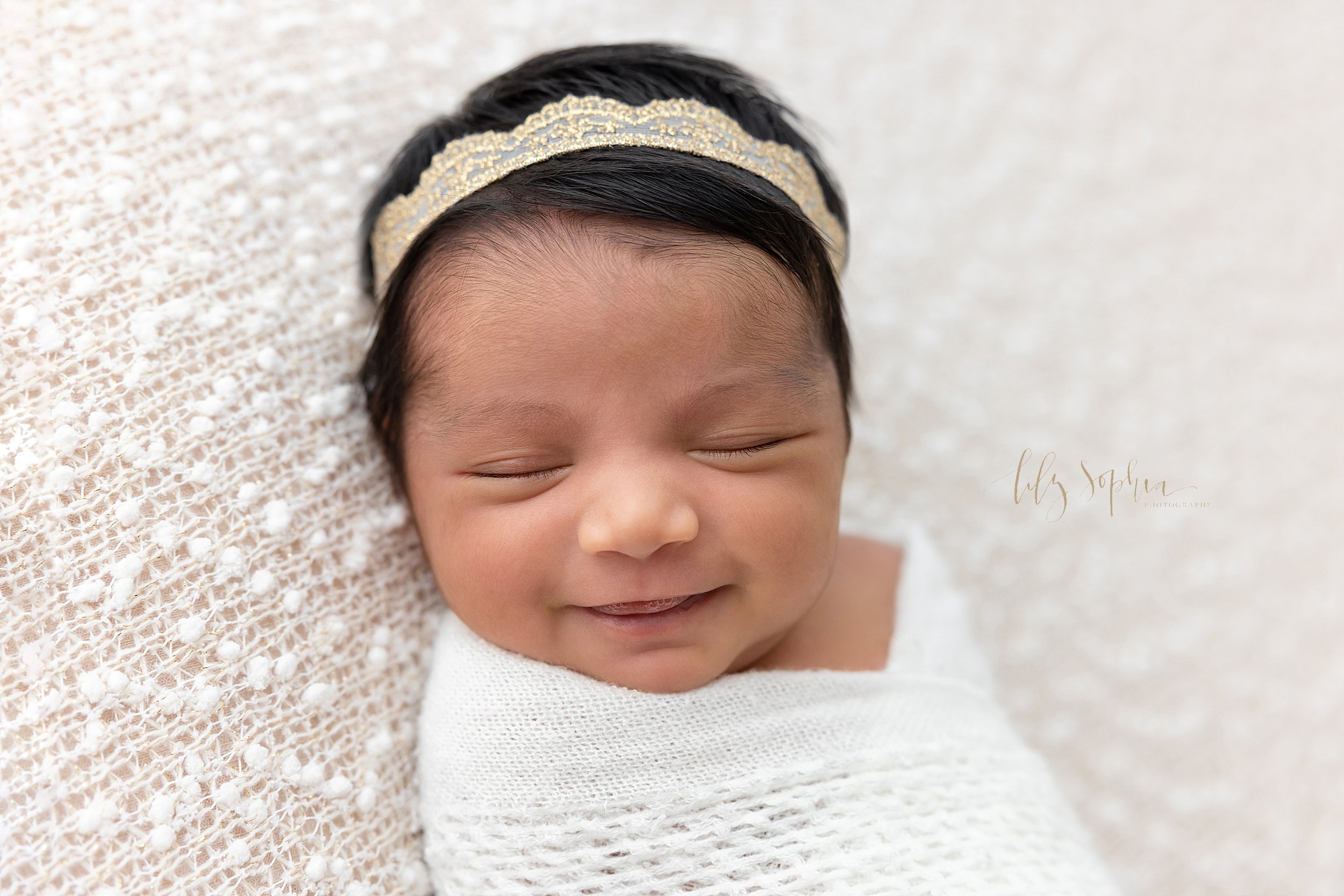  Newborn portrait of an Indian baby girl as she smiles in her sleep taken in a natural light studio near Virginia Highlands in Atlanta. 