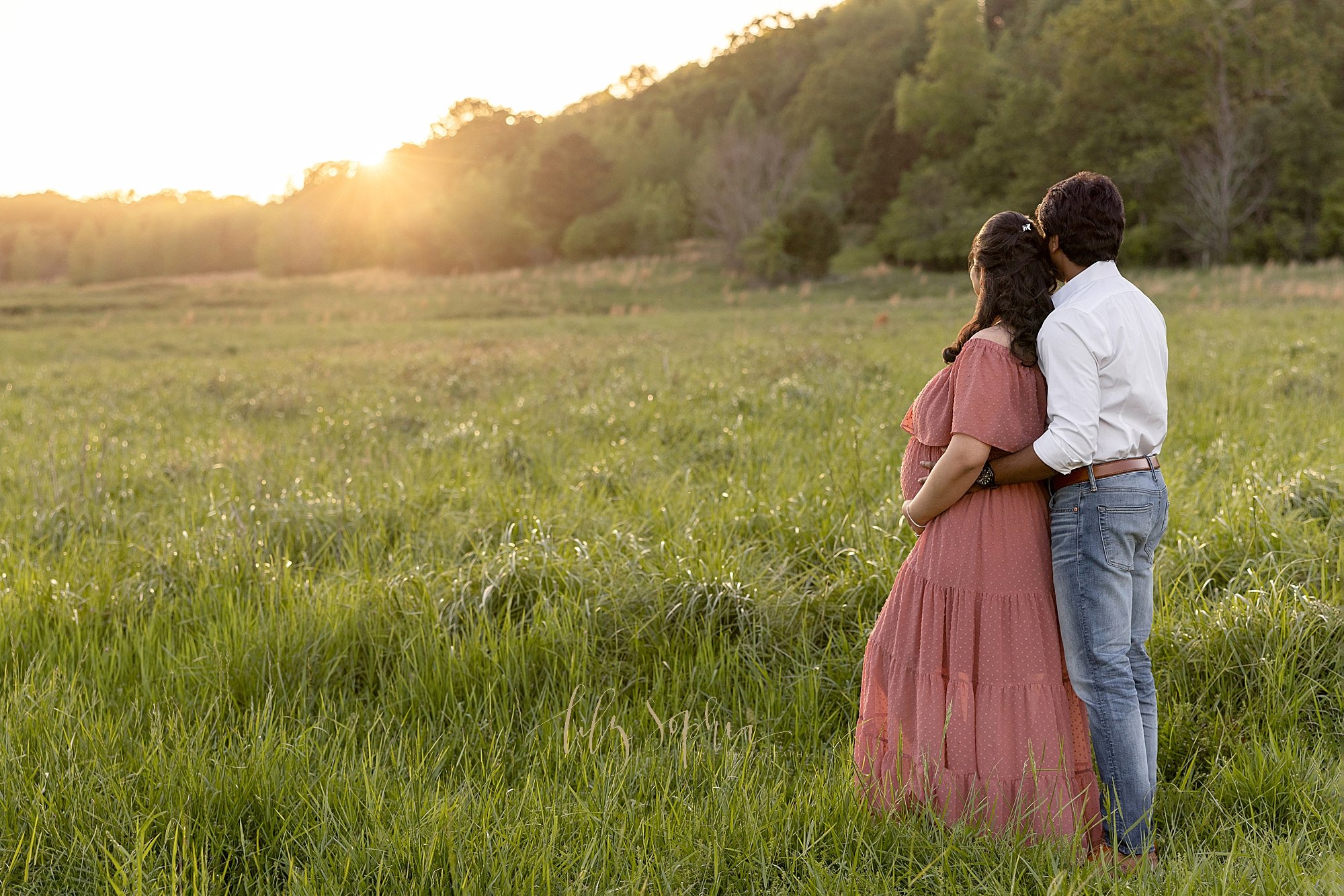  Maternity picture of an expectant couple standing in an Atlanta field admiring the sunset as the couple looks to the future. 