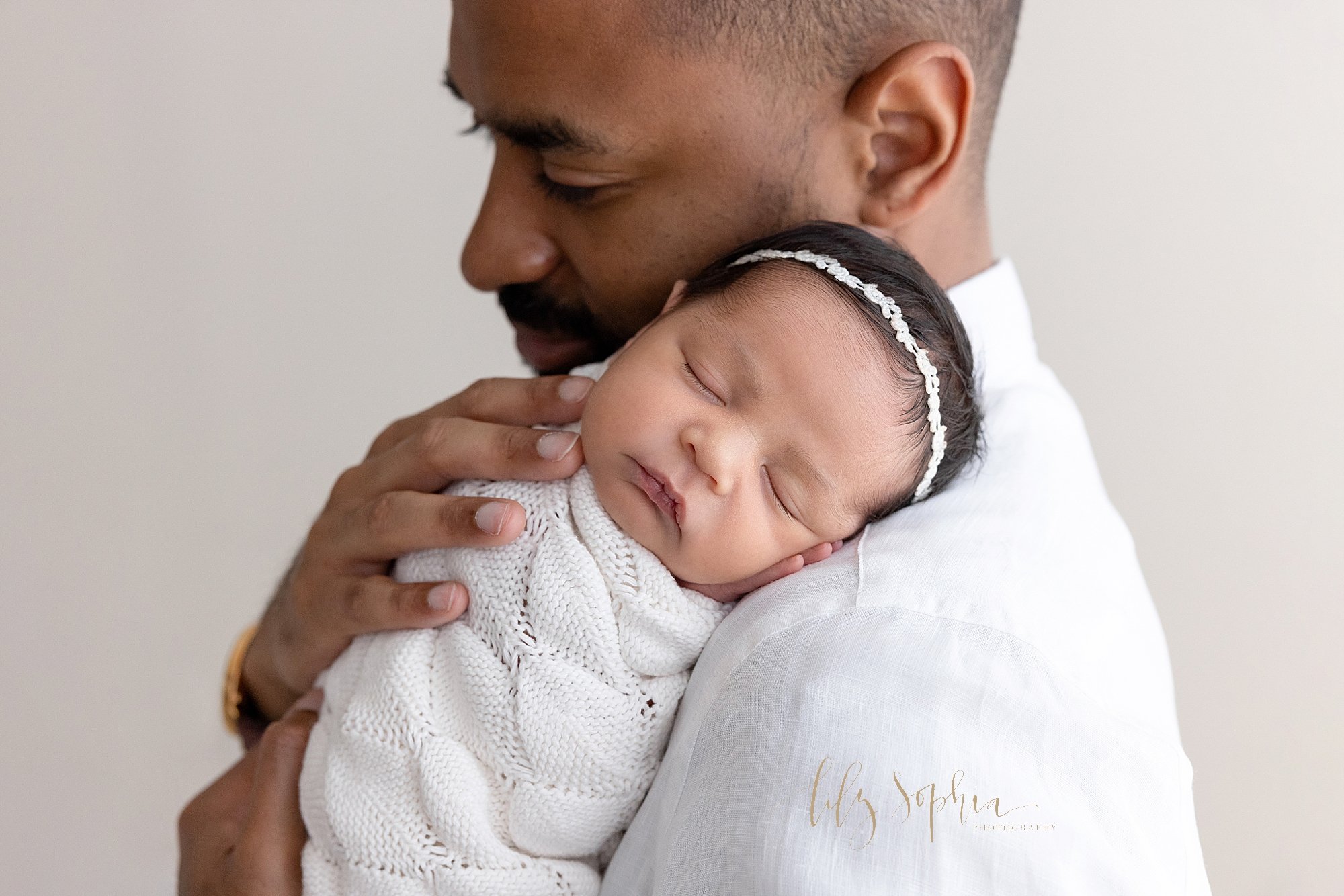  Newborn photo of an African-American father as he holds his peacefully sleeping newborn baby girl on his shoulder taken in a natural light studio near Smyrna in Atlanta. 