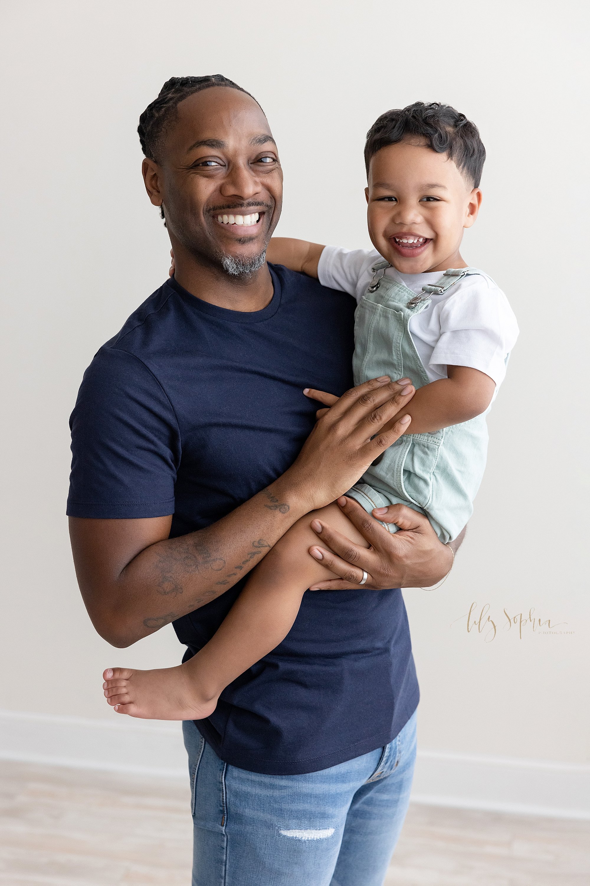  Family photo of an African-American father holding his toddler son in his arms taken near Poncey Highlands in Atlanta in a studio using natural light. 