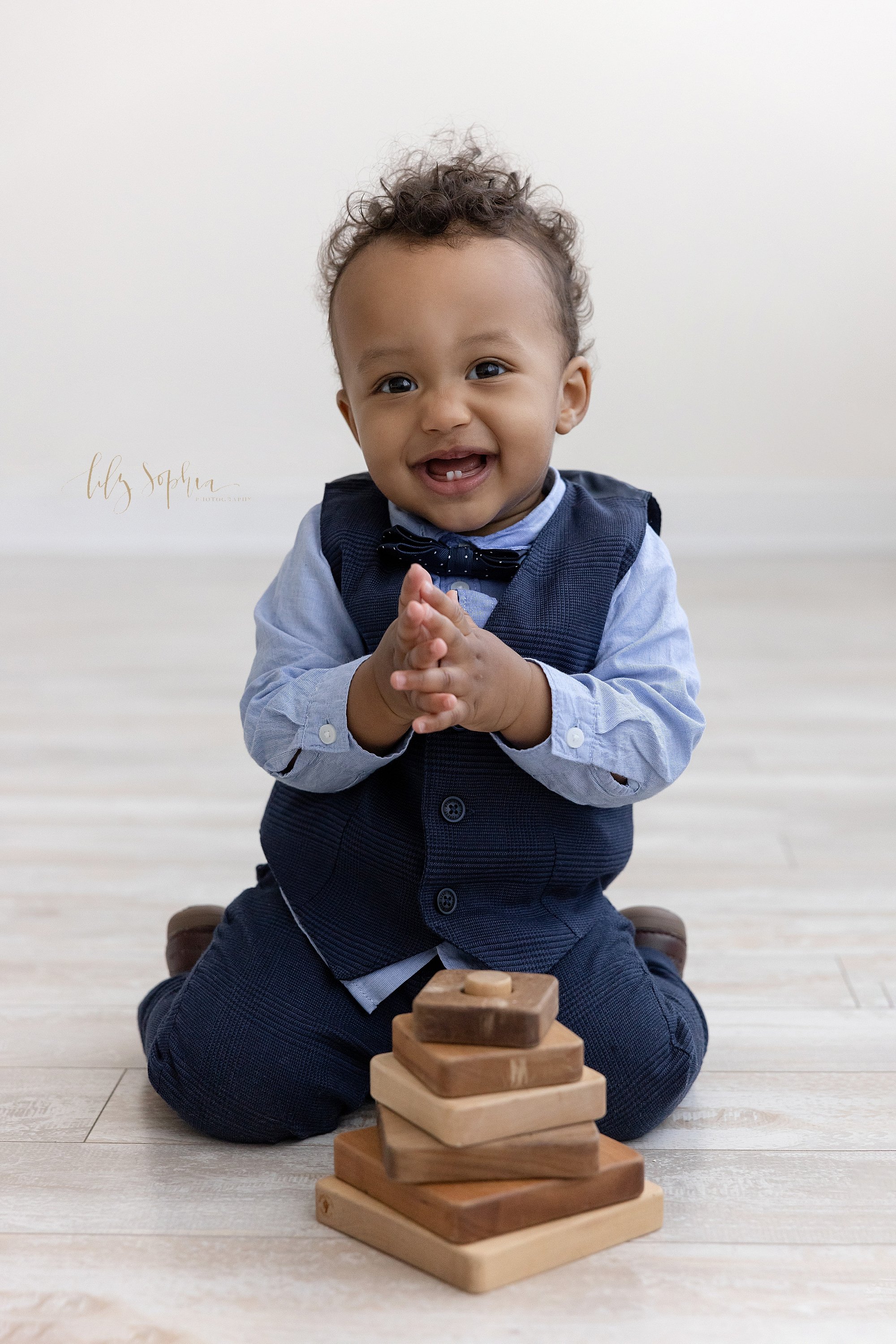  Proud one year old claps his hands after putting the last piece on a wooden stacking toy to celebrate his first birthday in a photography studio near Ansley Park that uses natural light. 