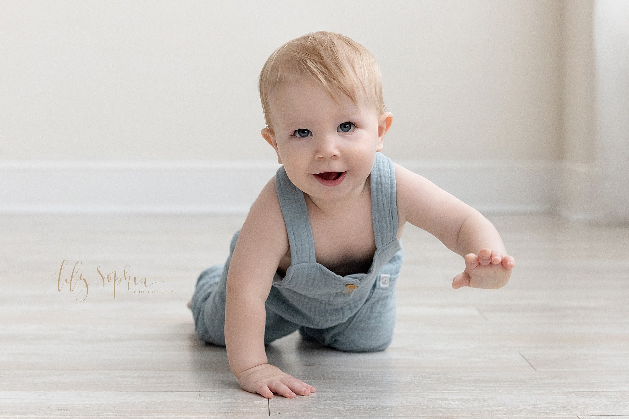  First birthday photo of a one year old little boy as he crawls across the floor of a photography studio using natural light near Decatur in Atlanta, Georgia. 