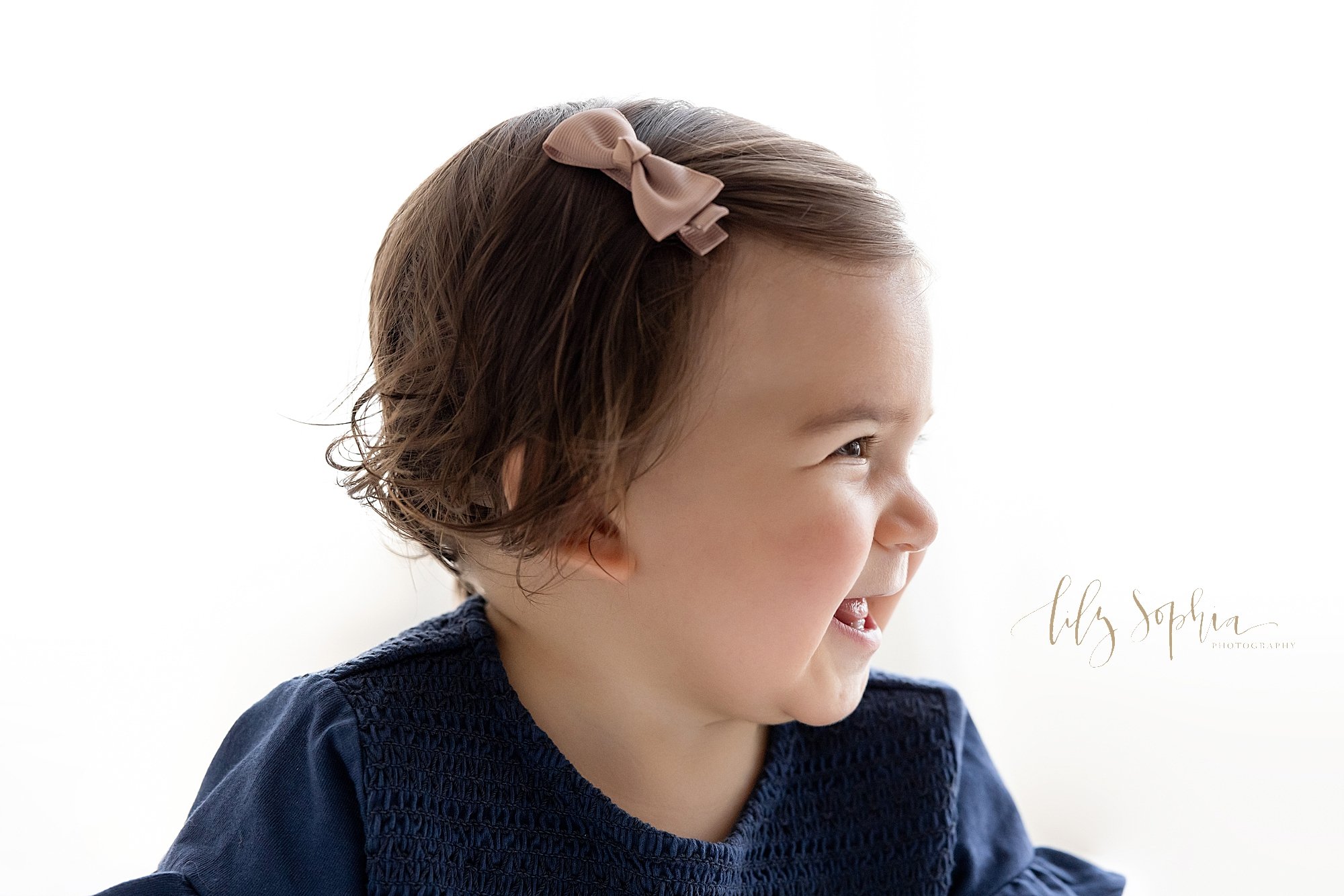  First birthday profile portrait of a one year old baby girl with natural light streaming in behind her in a studio located near Buckhead in Atlanta. 