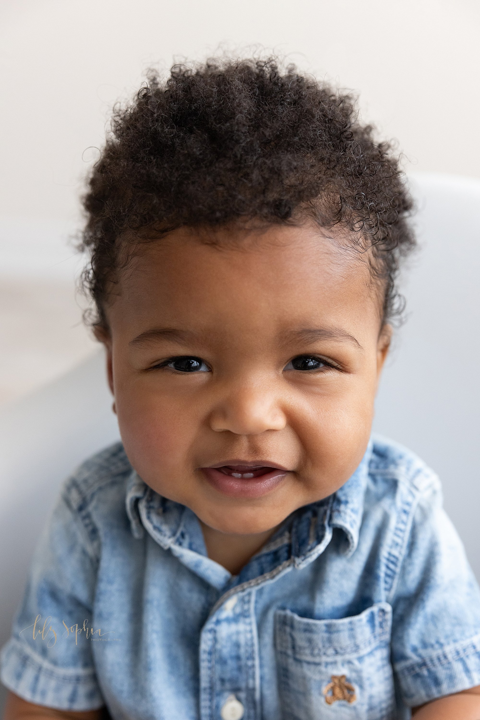  Baby portrait of an African-American nine month old baby boy with his tiny bottom teeth showing taken in a natural light studio near Decatur in Atlanta, Georgia. 