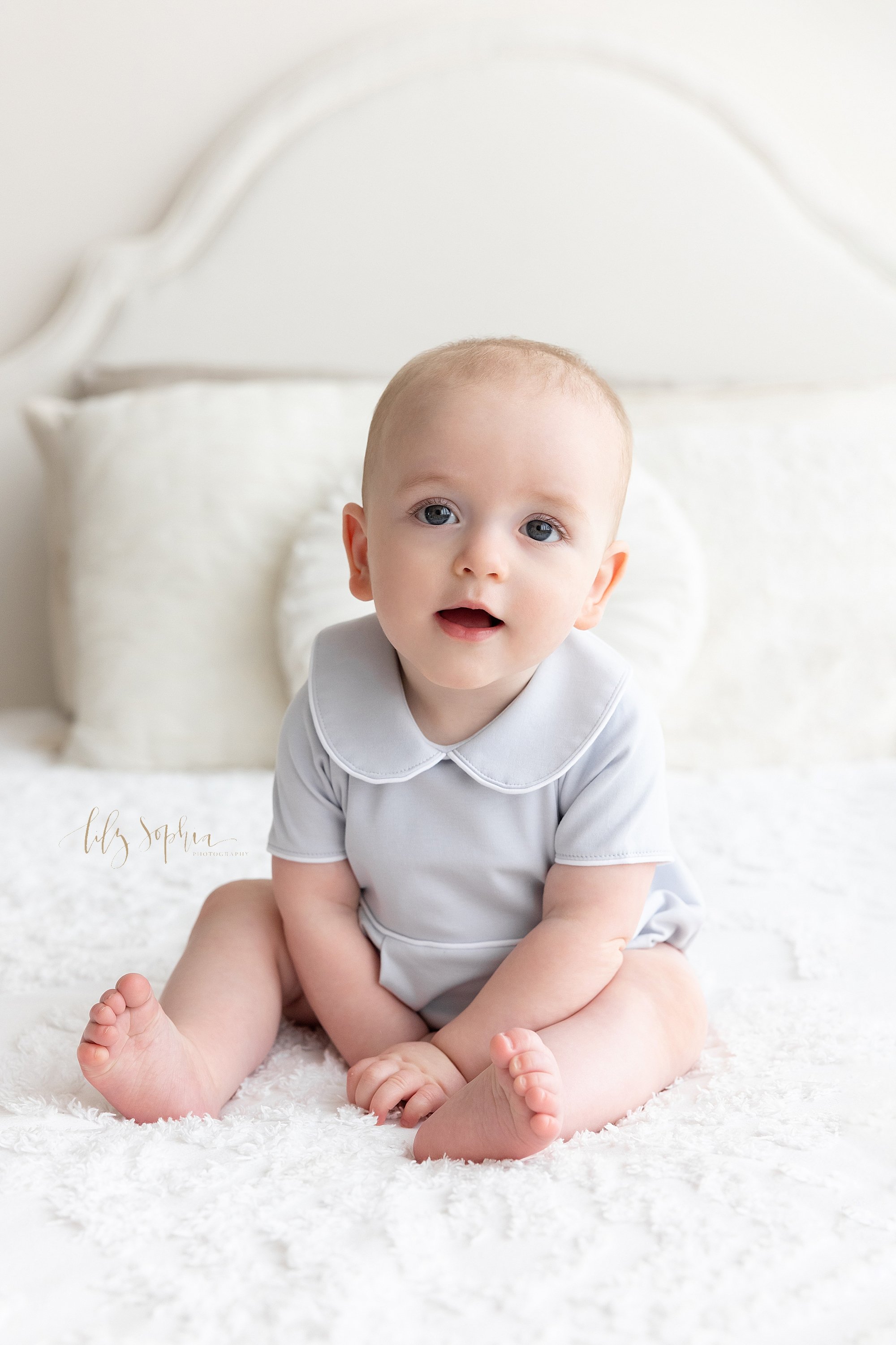  Milestone portrait of a baby boy as he sits atop a bed in a studio near Virginia Highlands in Atlanta, Georgia that uses natural light. 