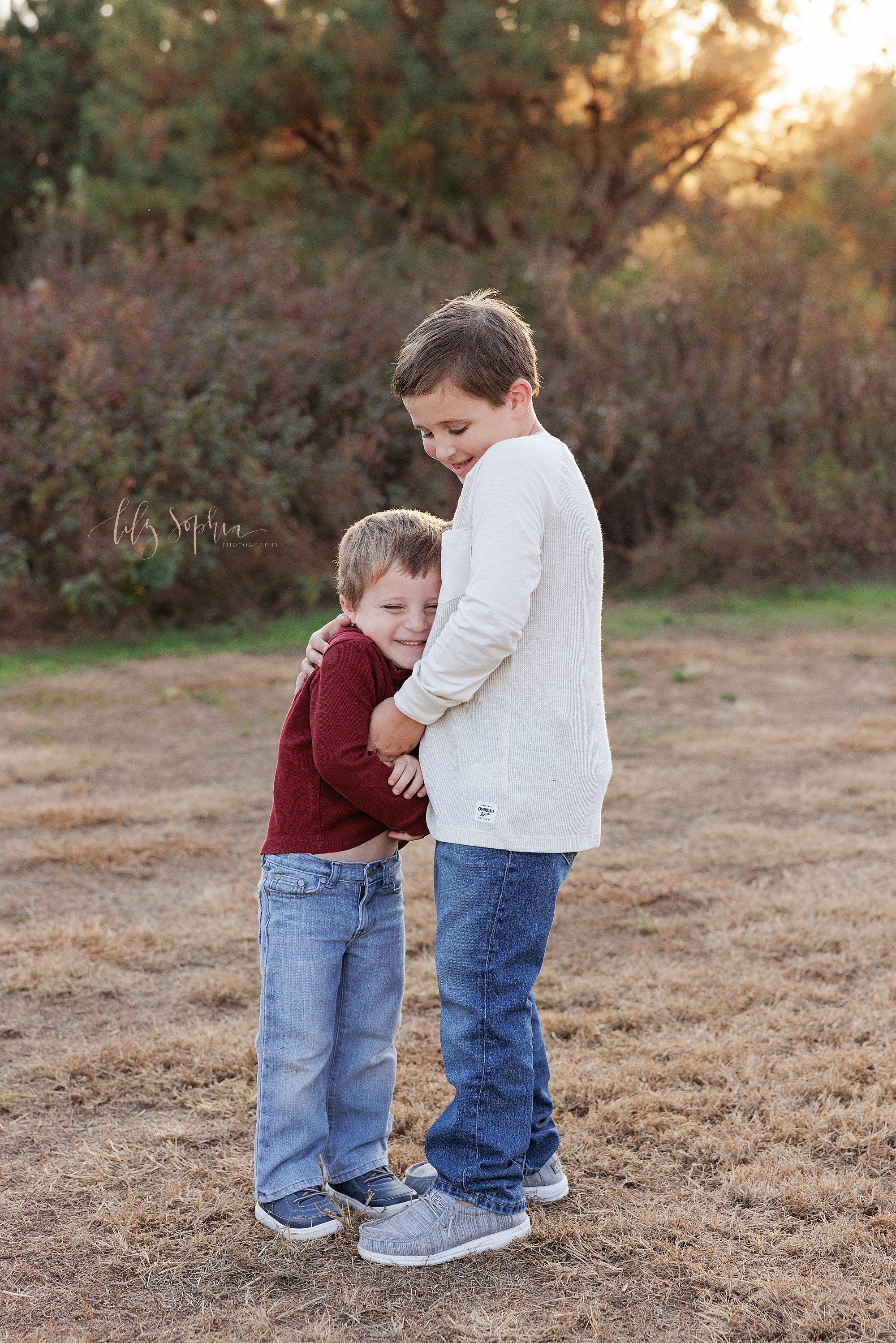  Capturing fun between two brothers as the elder brother tickles the younger brother for a family photo taken during autumn in a field near Atlanta, Georgia at sunset. 