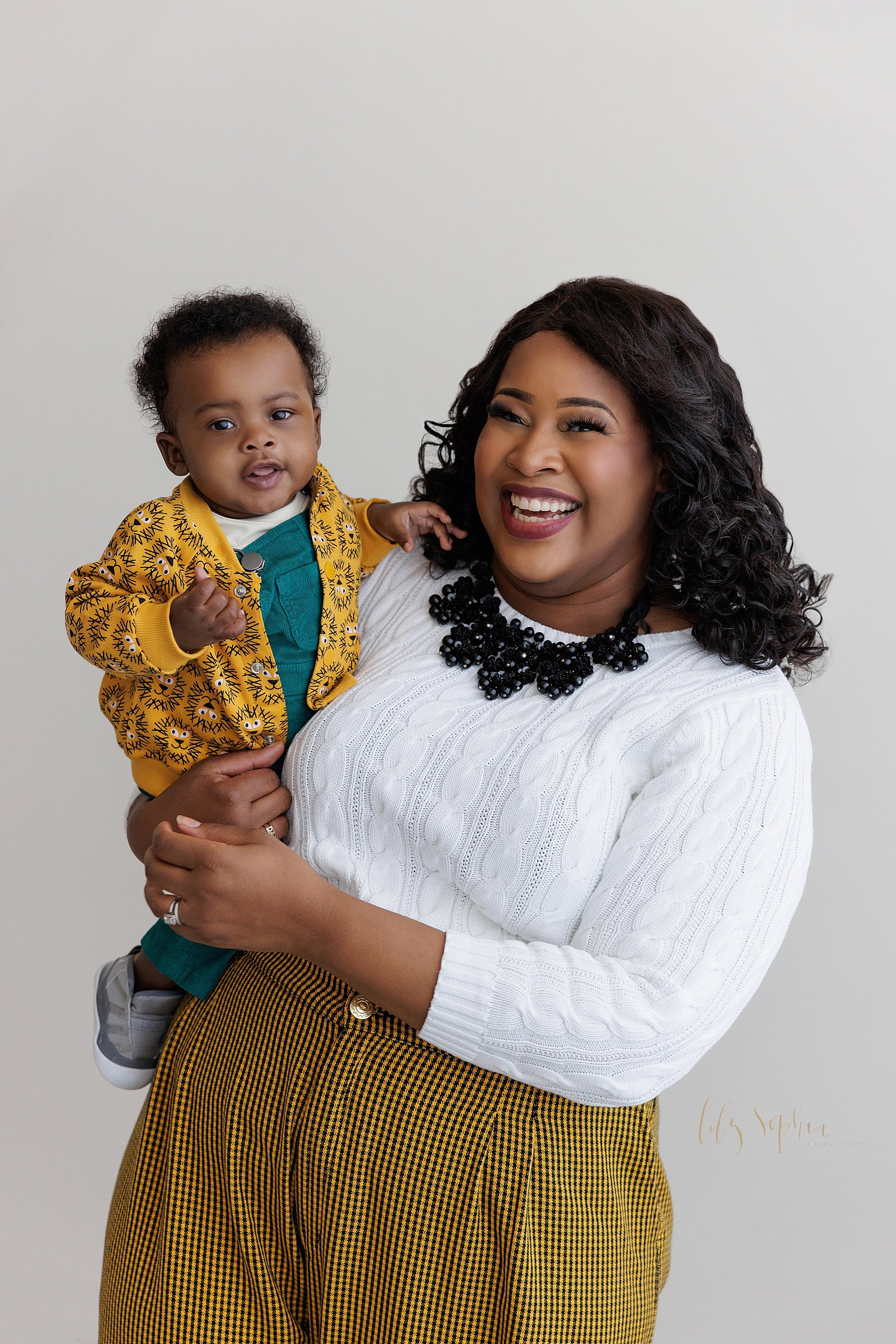  Family photo of a happy African-American mother as she holds her baby boy in her right arm taken near Decatur in Atlanta in a natural light studio. 