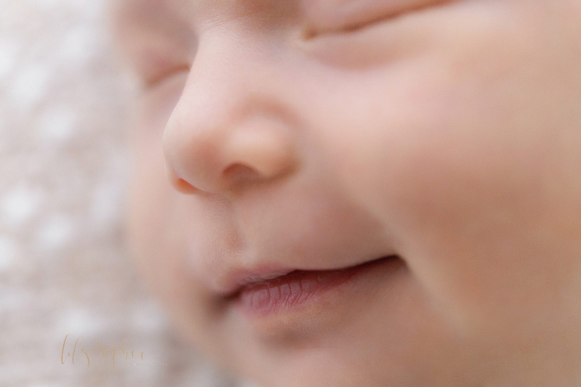  Close-up photo of a newborn baby girl’s face featuring her button nose and her milky lips taken in a natural light studio near Virginia Highlands in Atlanta, Georgia. 