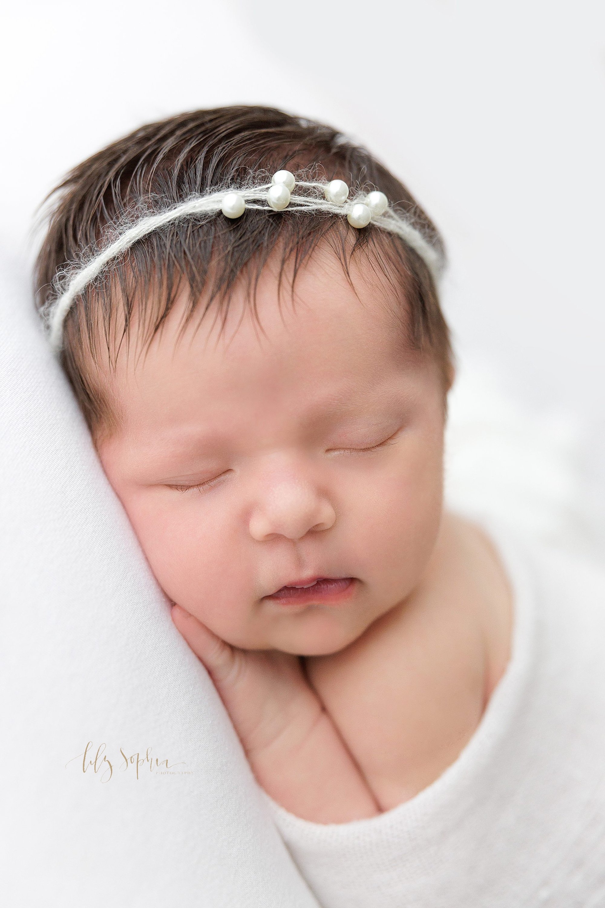  Newborn portrait of a newborn baby girl peacefully sleeping with her right hand under her chin taken using natural light near Morningside in Atlanta in a photography studio. 
