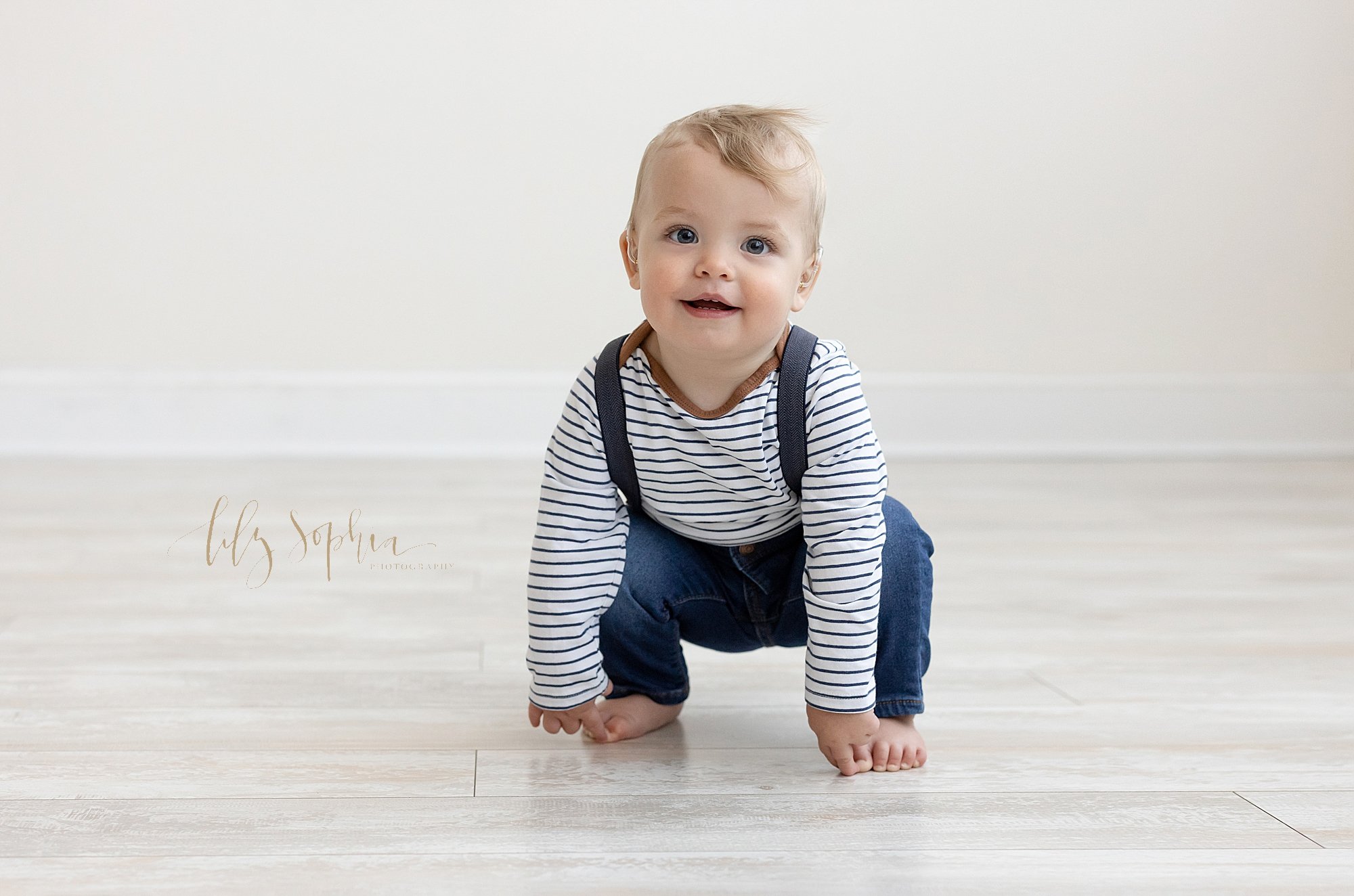  Photo shoot for a one year old little boy’s first birthday as he squats to touch his toes in a natural light studio near Old Fourth Ward in Atlanta, Georgia. 