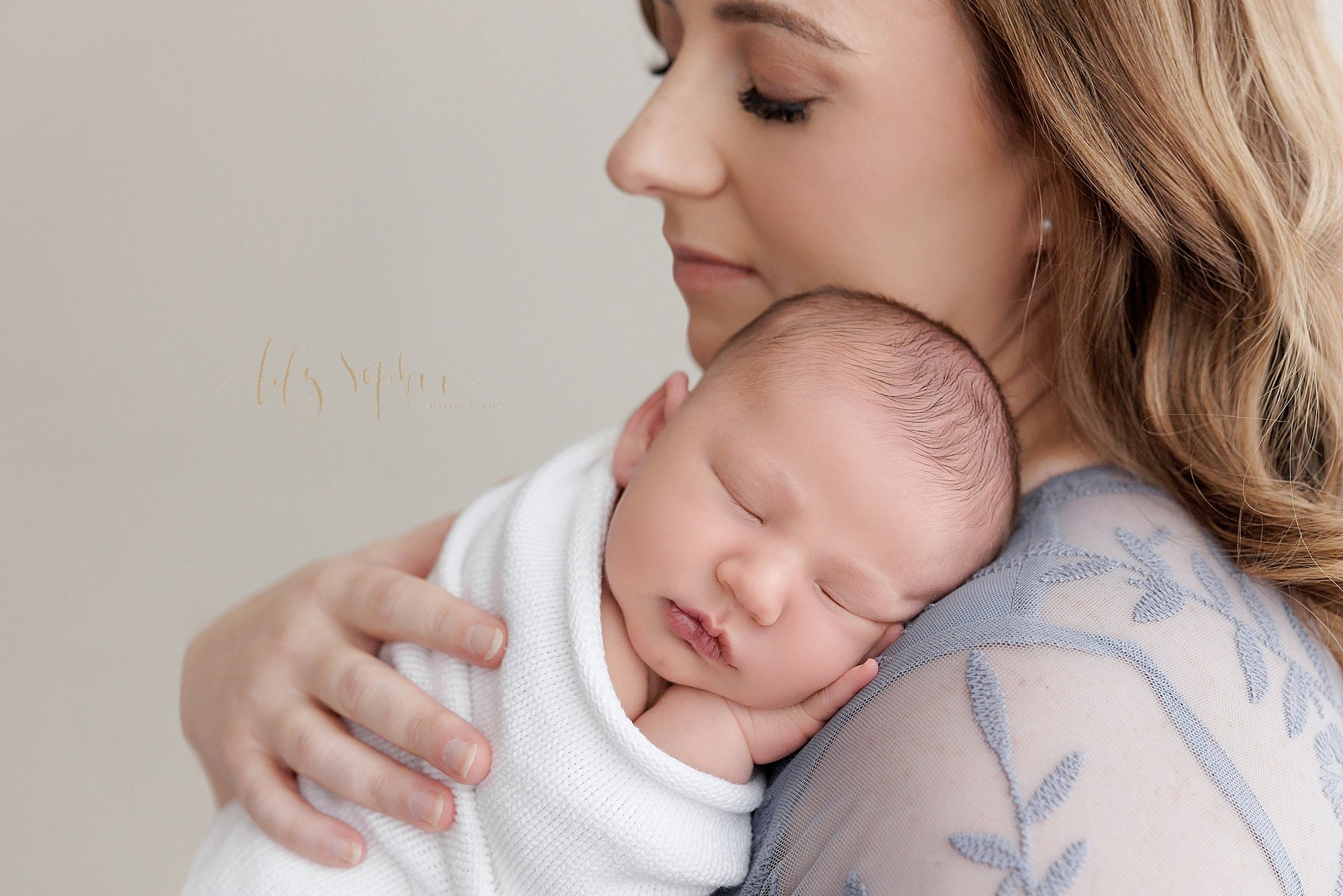  Newborn photo of a newborn baby boy as he is held on the left shoulder of his mother as she stands in a photography studio near Roswell in Atlanta that uses natural light. 